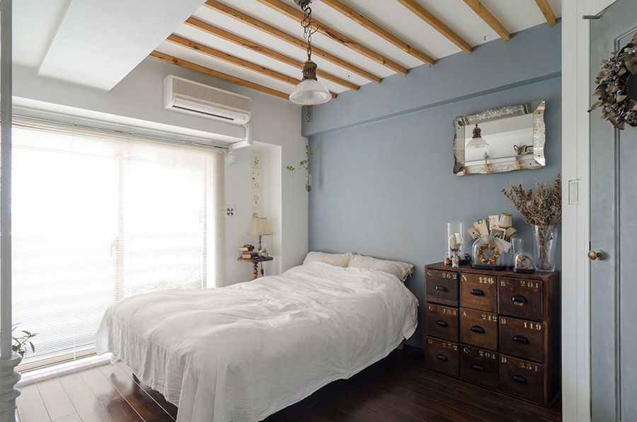 夫のベッドルーム。ブルーグレーの塗装、天井の梁、ドアの塗装はすべてDIY。南仏のアトリエをイメージした。