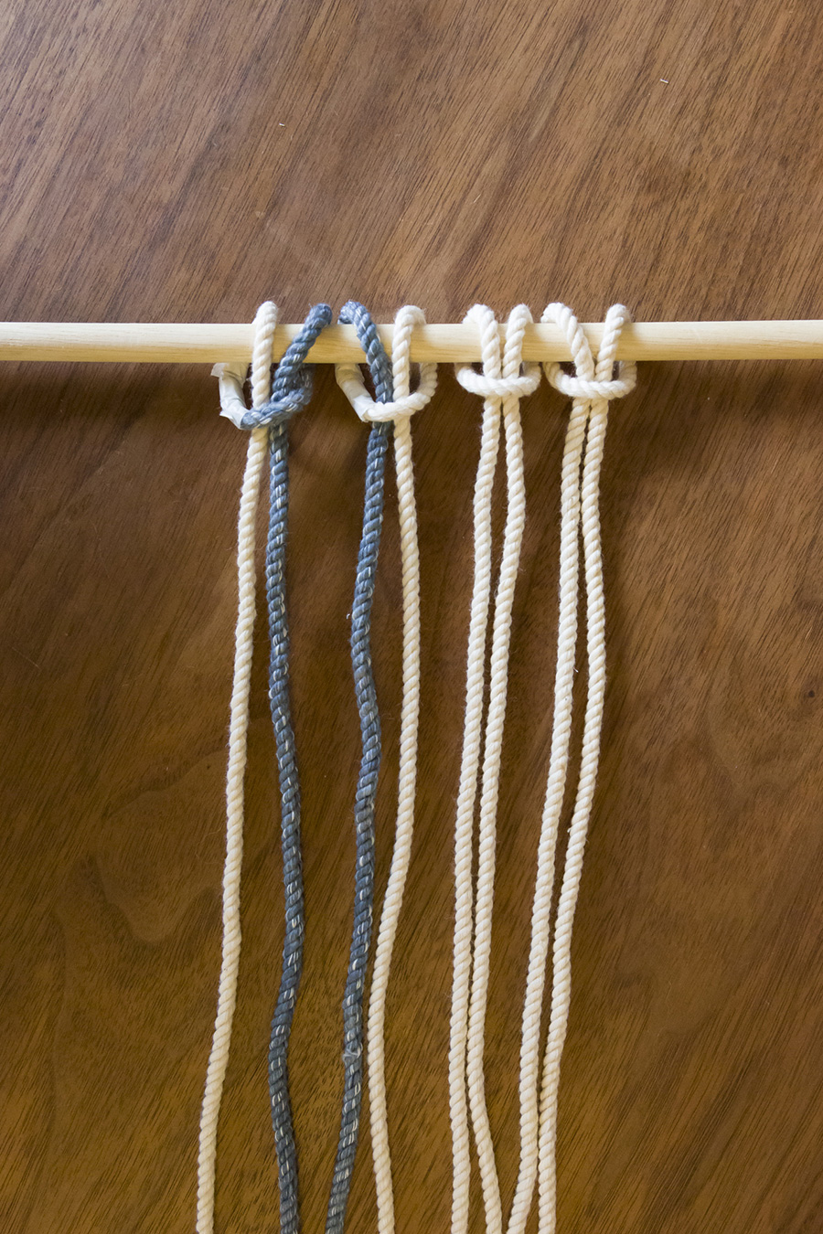 ①４本のロープを２つに折って丸棒に結び（わかりやすいように一部色を変えています）、８本のロープを編んでいく。