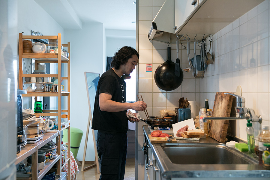 家に泊まりに来た後輩のためにキッチンでステーキサンドを作る龍之進さん。
