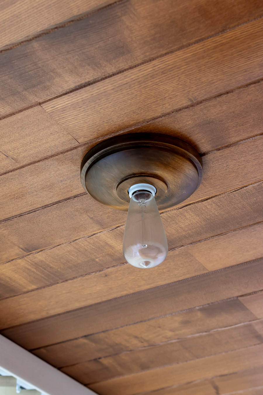 板張り天井には木材の台座付きブラケットライトを。