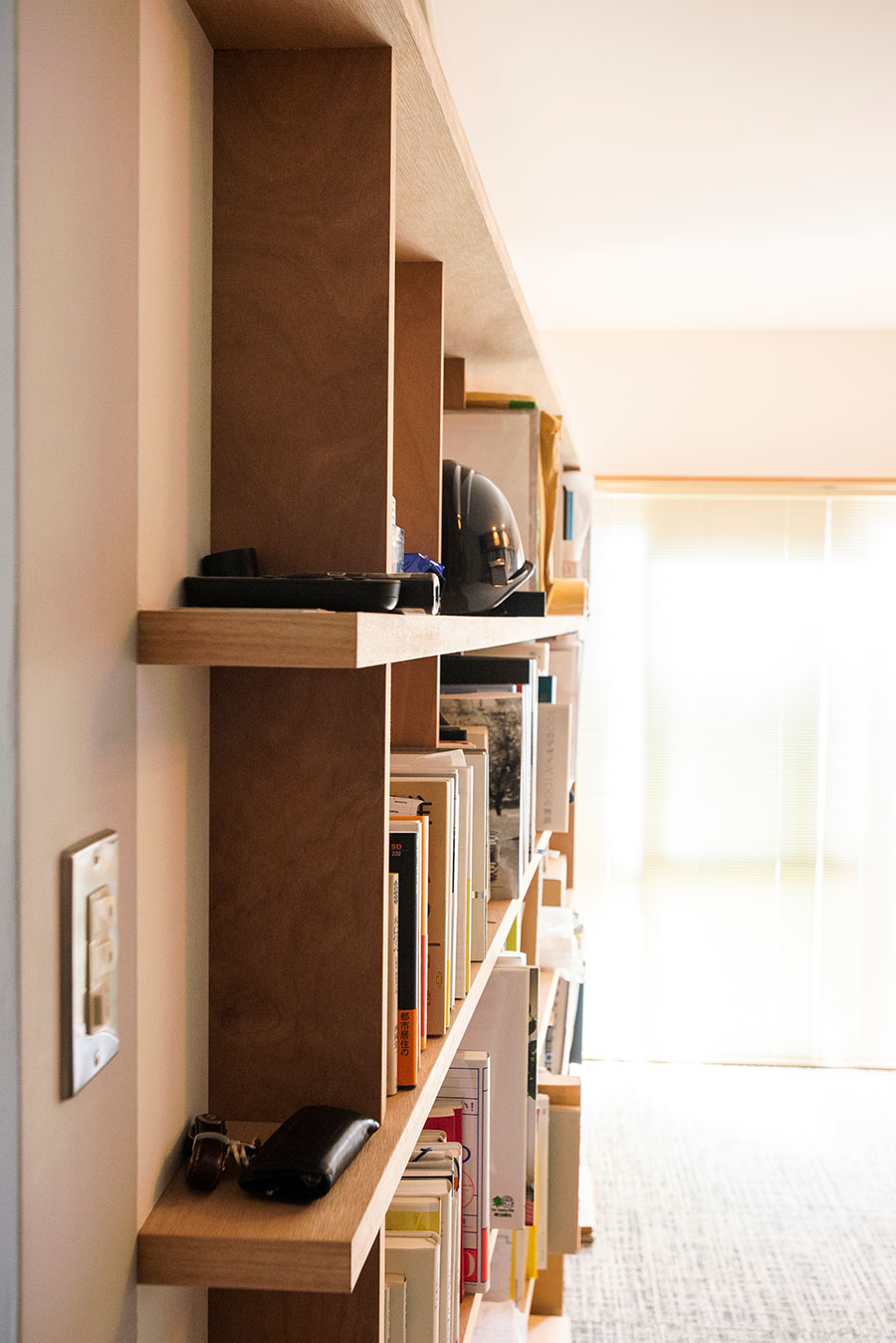 自らデザインし壁面に造作した棚は、手前から奥に行くほど奥行きが深くなっている。色々な幅の本の収納に対応。　　
