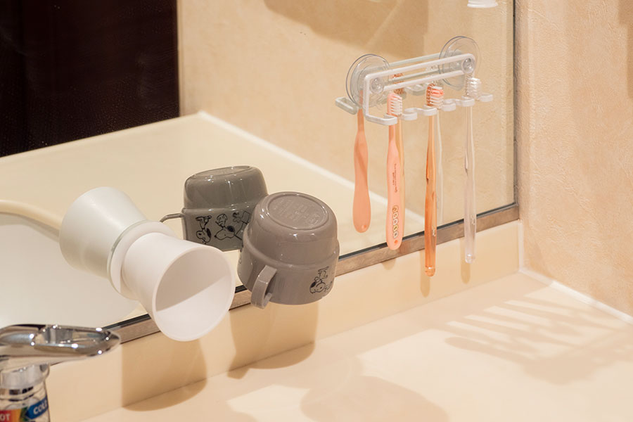 歯ブラシやコップを吊り収納に。洗面台上はできるだけモノを置かないことで掃除が楽になる。