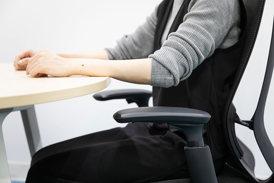 椅子に座ったままデスクに近づき、机の上に手を置き、肘が約90°になるまで座面の高さを調整する。