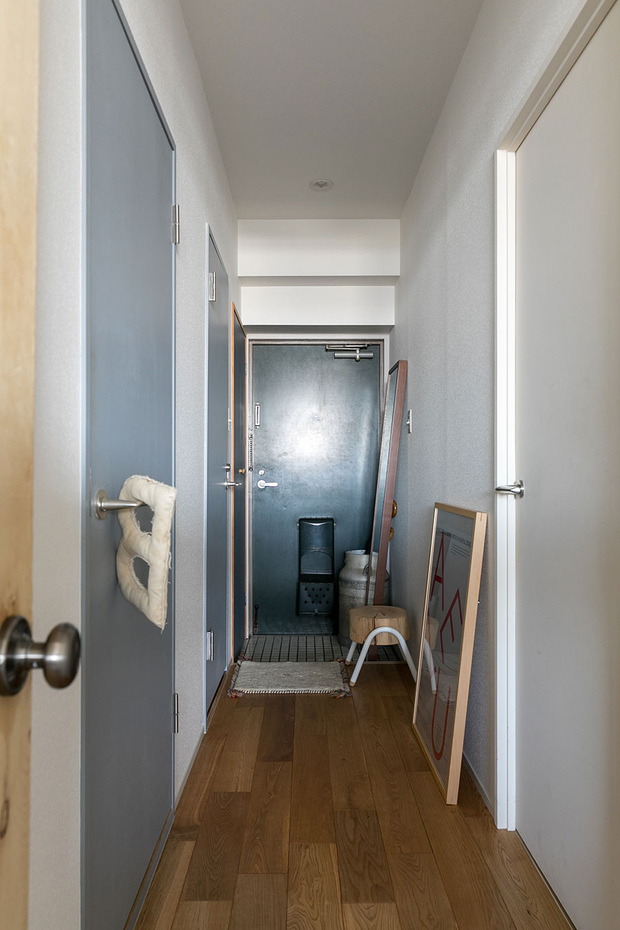 床材は幅広のオークの無垢材。右側に寝室、左側にトイレと洗面所。扉をグレーに。