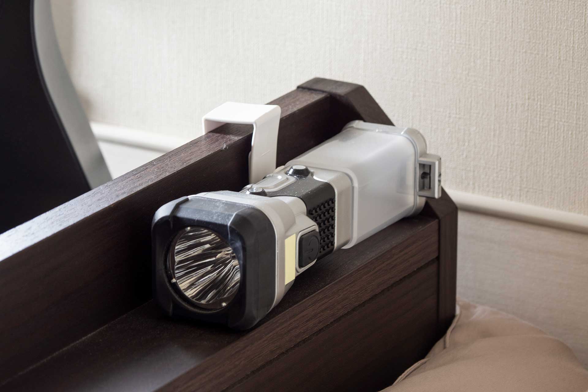 ベッドヘッドに置いている懐中電灯兼ランタン。100円ショップのキッチン扉用フックを使って固定。