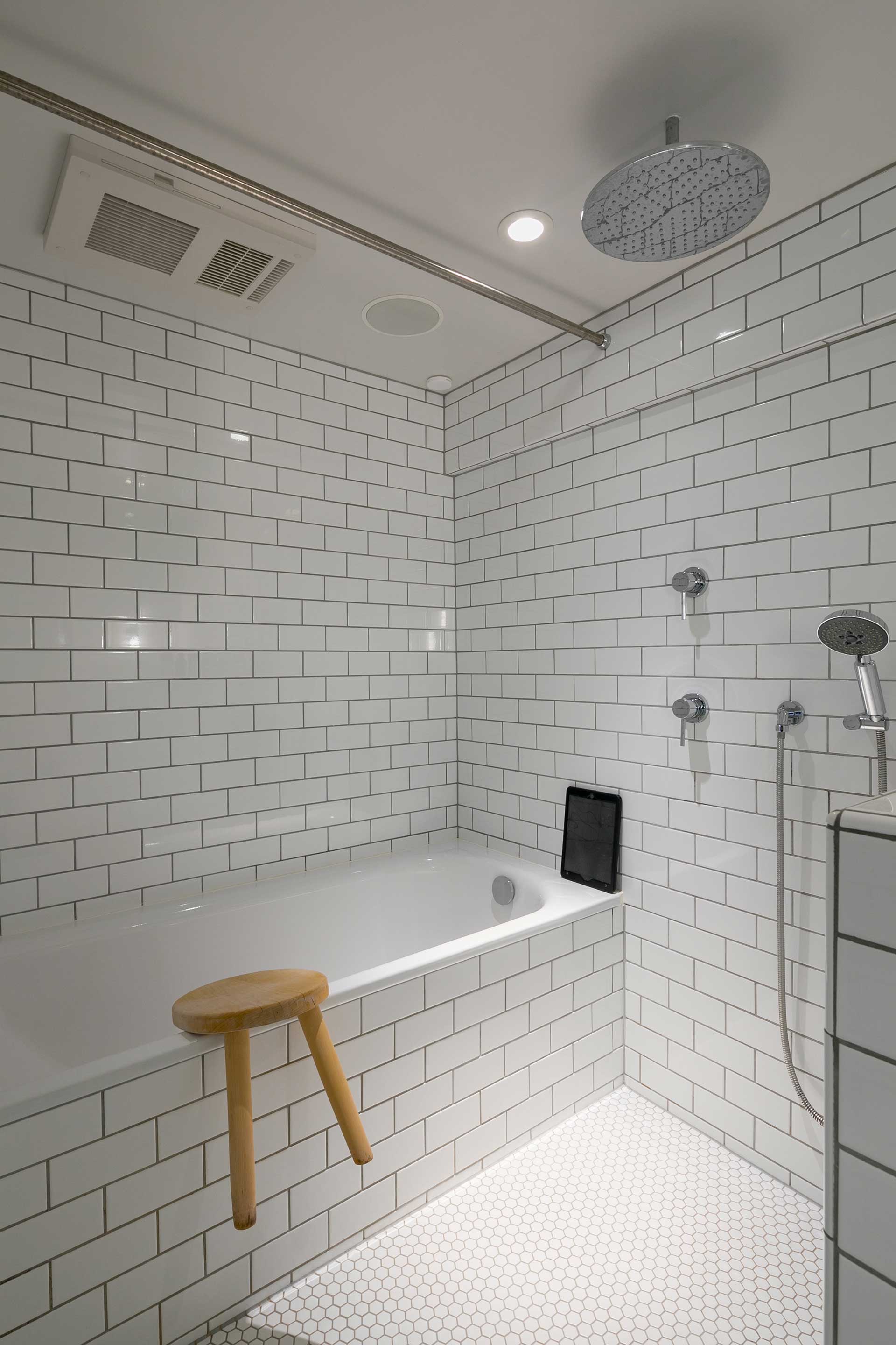 レインシャワーやBluetooth搭載のスピーカーを設置したホテルライクなバスルーム。壁と浴槽はサブウェイタイル、床はモザイクタイルを使用。