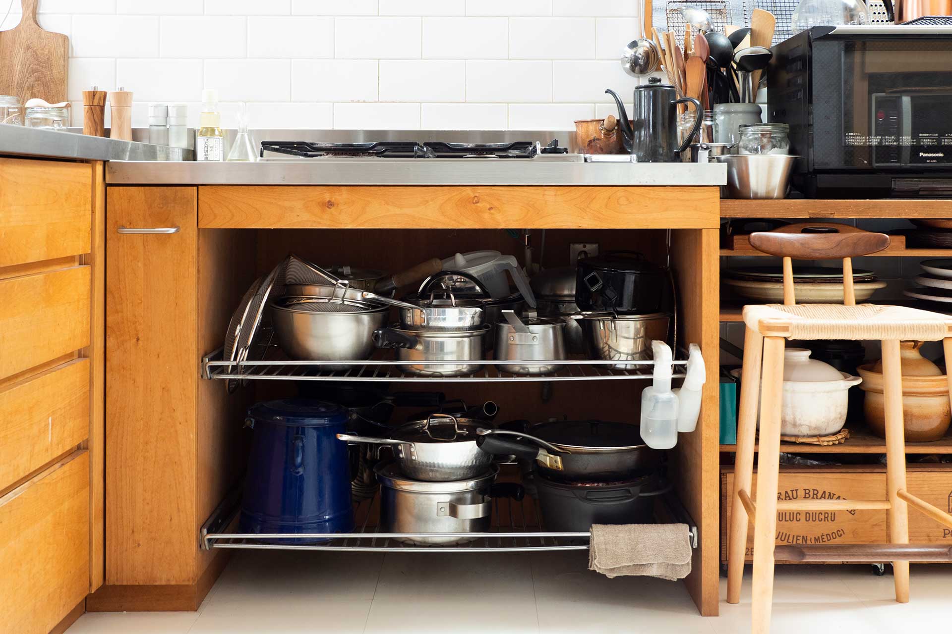 建築家とオーダーキッチンの家具屋さんに相談し、ステンレスと無垢材を組み合わせて造作した温かみのあるキッチン。オープンな収納に使い込まれた台所道具が並ぶ。