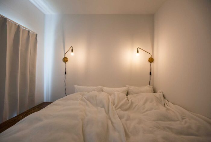 シンプルなベッドルームには、壁付けのブラケット照明をシンメトリーに。