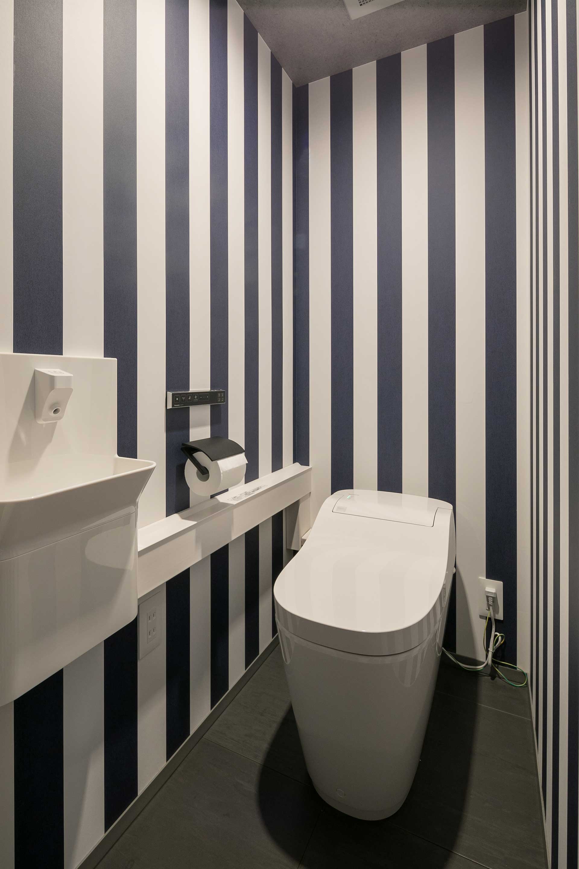 縦方向に広がりを感じさせるストライプ柄の壁紙が印象的なトイレ。