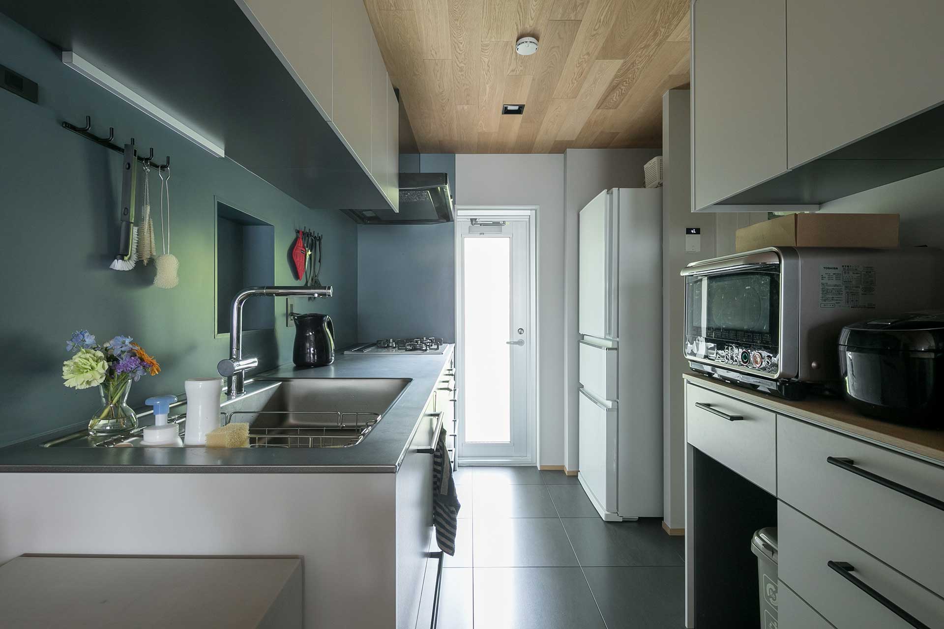 エメラルドグリーンの壁紙とオークの天井が美しい造作のキッチン