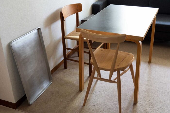 アルヴァ・アアルトの50年代のテーブルに、アーコール、ボーエ・モーエンセンのヴィンテージのイスを。アルミの四角いトレーもインテリアのひとつ。