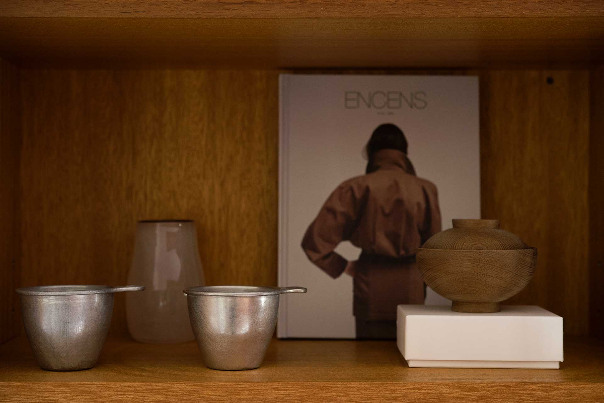 収納棚の扉の中。木の器とバックの本の茶色に、アルミのコップをコーディネート。