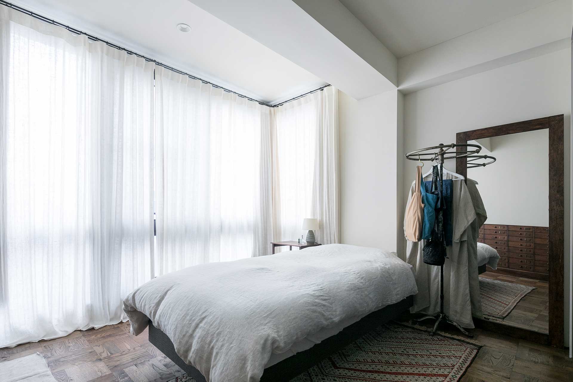 天井からのたっぷりとしたドレープのリネンのカーテン越しの光が心地よい。寝室なので遮光カーテンと併用している。