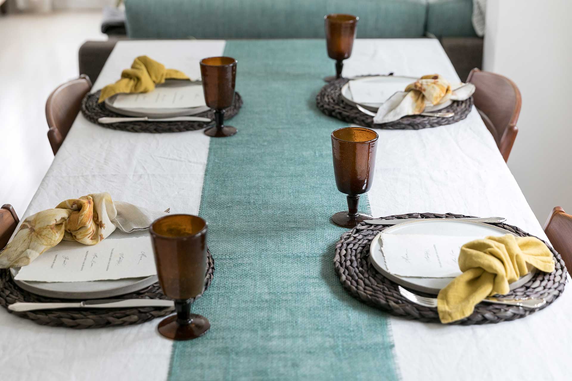 まず、白のリネンのテーブルクロスに、素材感のあるグリーンのテーブルランナーを敷き、４人分のお皿とカトラリーをセット。