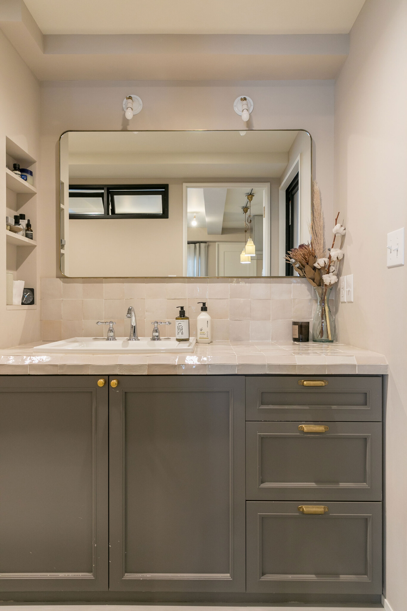 キッチンと同じタイルを洗面所にはまっすぐに貼り、表情の違いを楽しむ。洗面所の扉もキッチンと同様、框仕上げに。鏡は『DEN PLUS EGG』オリジナル。