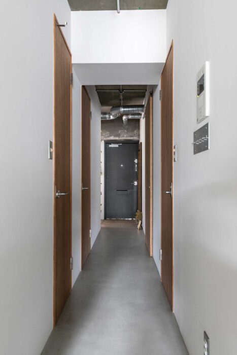 玄関から廊下、そしてリビングまでモルタルの土間が続く。ドアは『ASSY』の標準のもの。手前左のドアがウォークインクローゼット。リビング側からも開けられる。