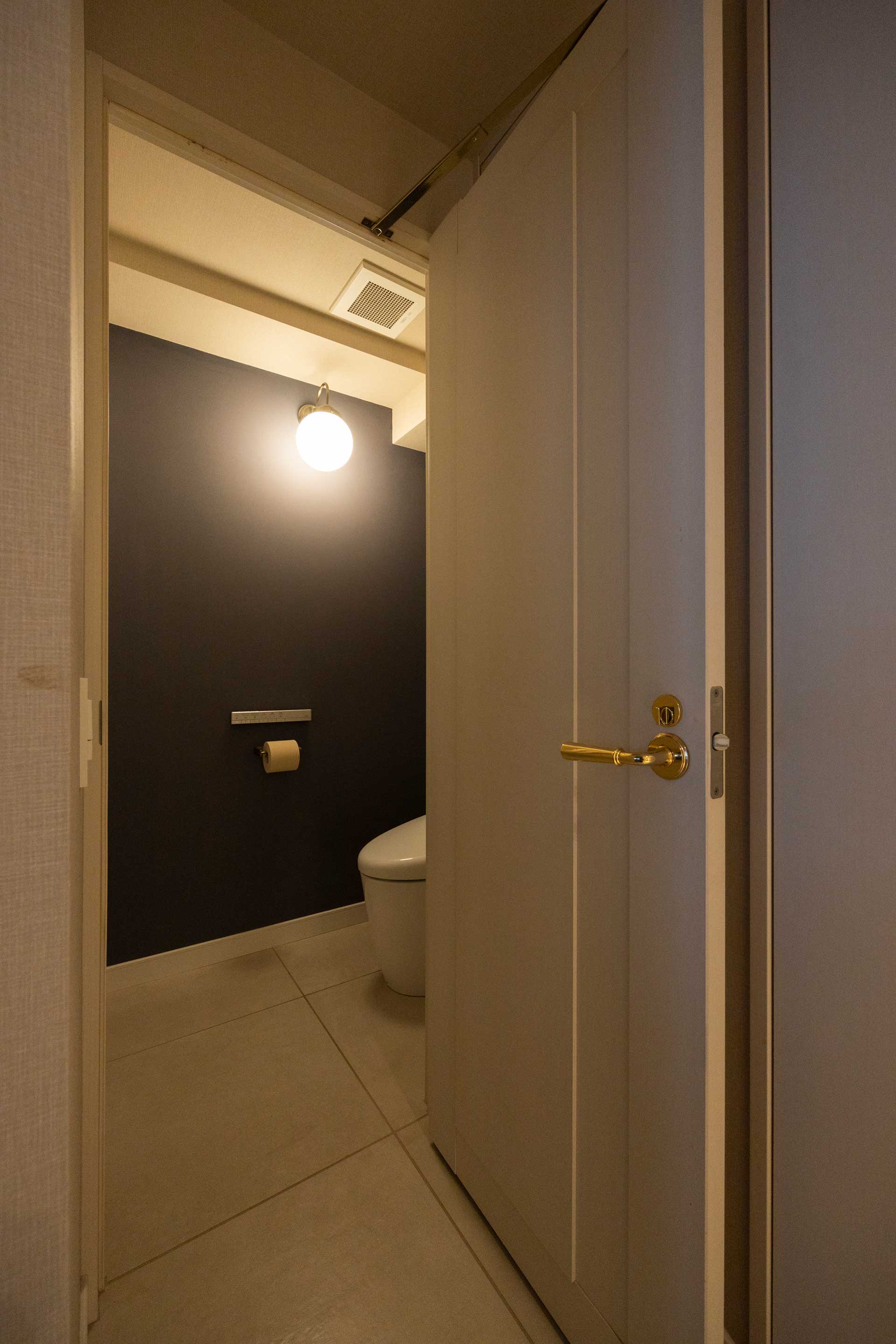 トイレの壁はいちばん濃いグレーを選択。真鍮のペーパーホルダー、業務用のシンプルなバーにこだわった。