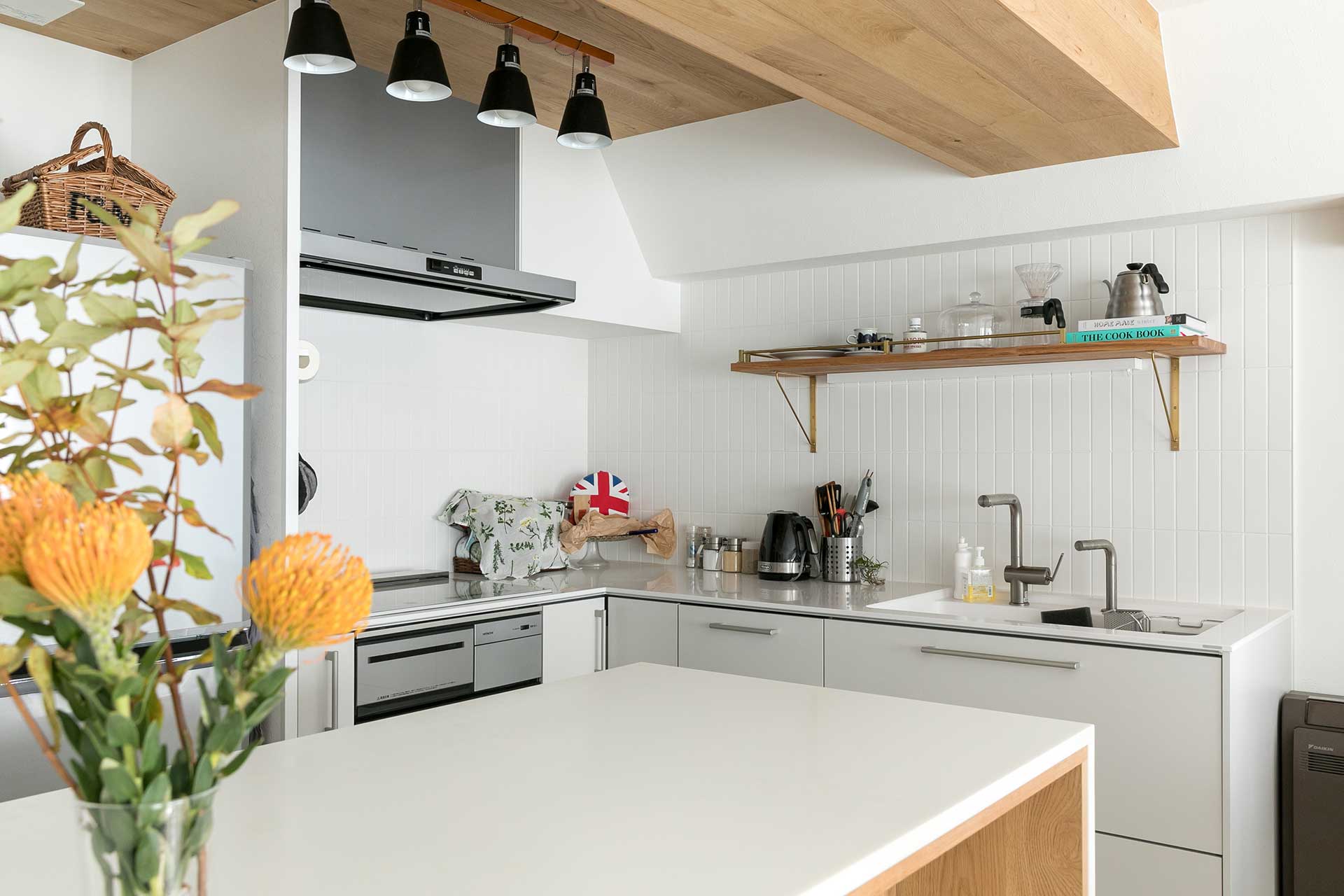 キッチンの天井や、作業台上にある梁には木目のパネリングを採用。白を基調とした空間のアクセントになっている。