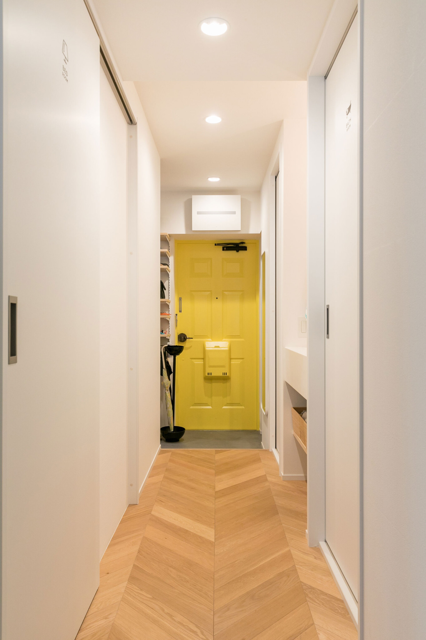 玄関ドアも黄色に塗装。フローリングはLDKと同じヘリンボーン張り。