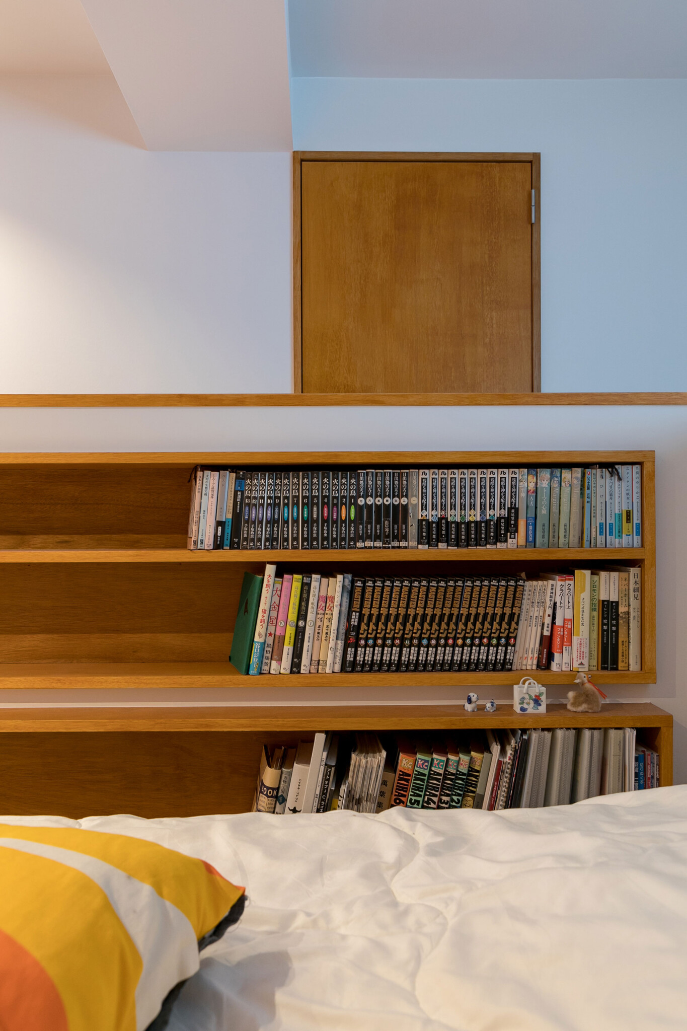 ベッドサイドには本棚を壁に埋め込んだ。本の種類に合わせて棚の高さと奥行きを変えた。まだまだ収納できる余裕がうれしい。