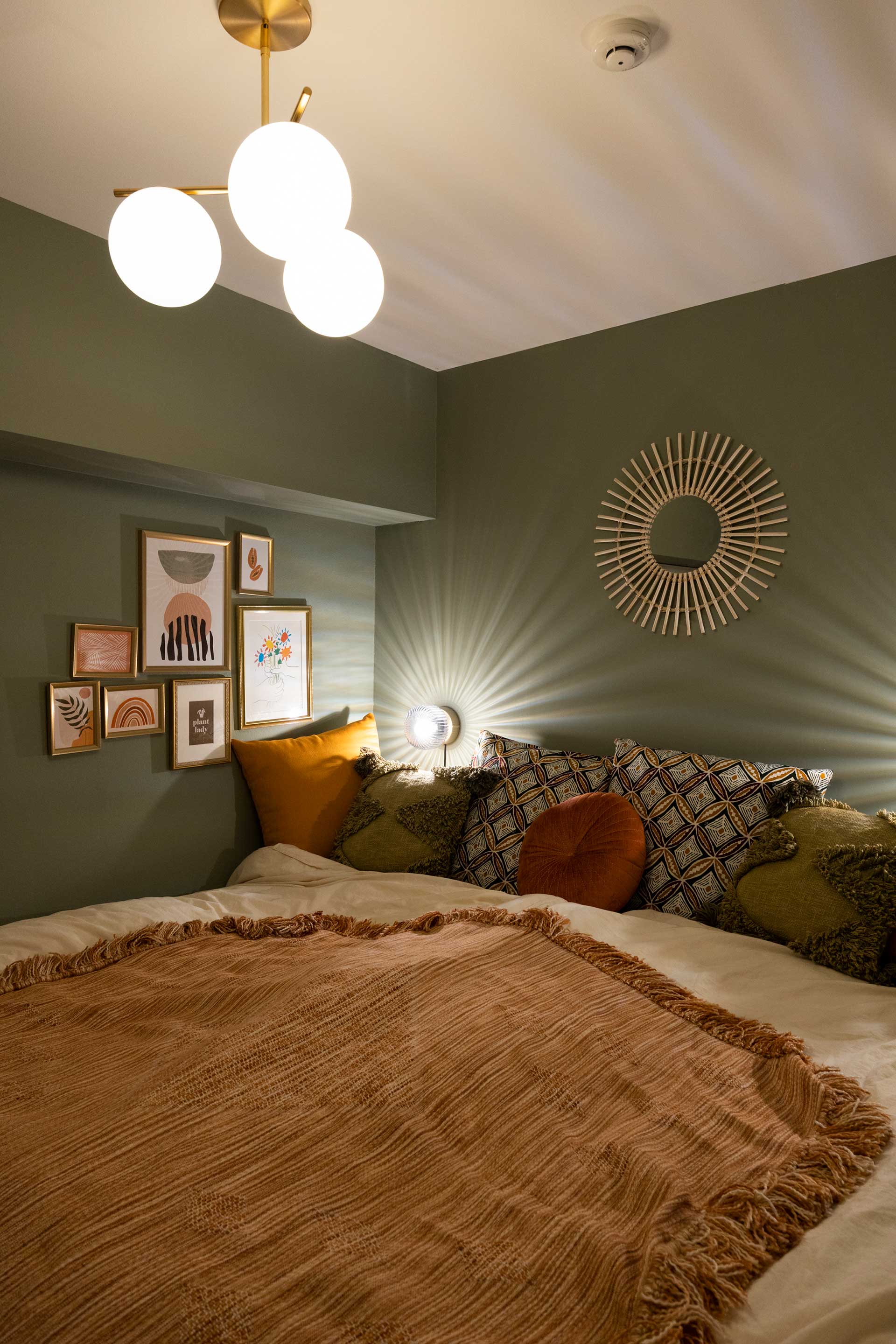 寝室の壁は落ち着いたグリーンに。照明器具は海外サイトで購入。「額は絵の色味をある程度合わせ、リズム良く飾ります」
