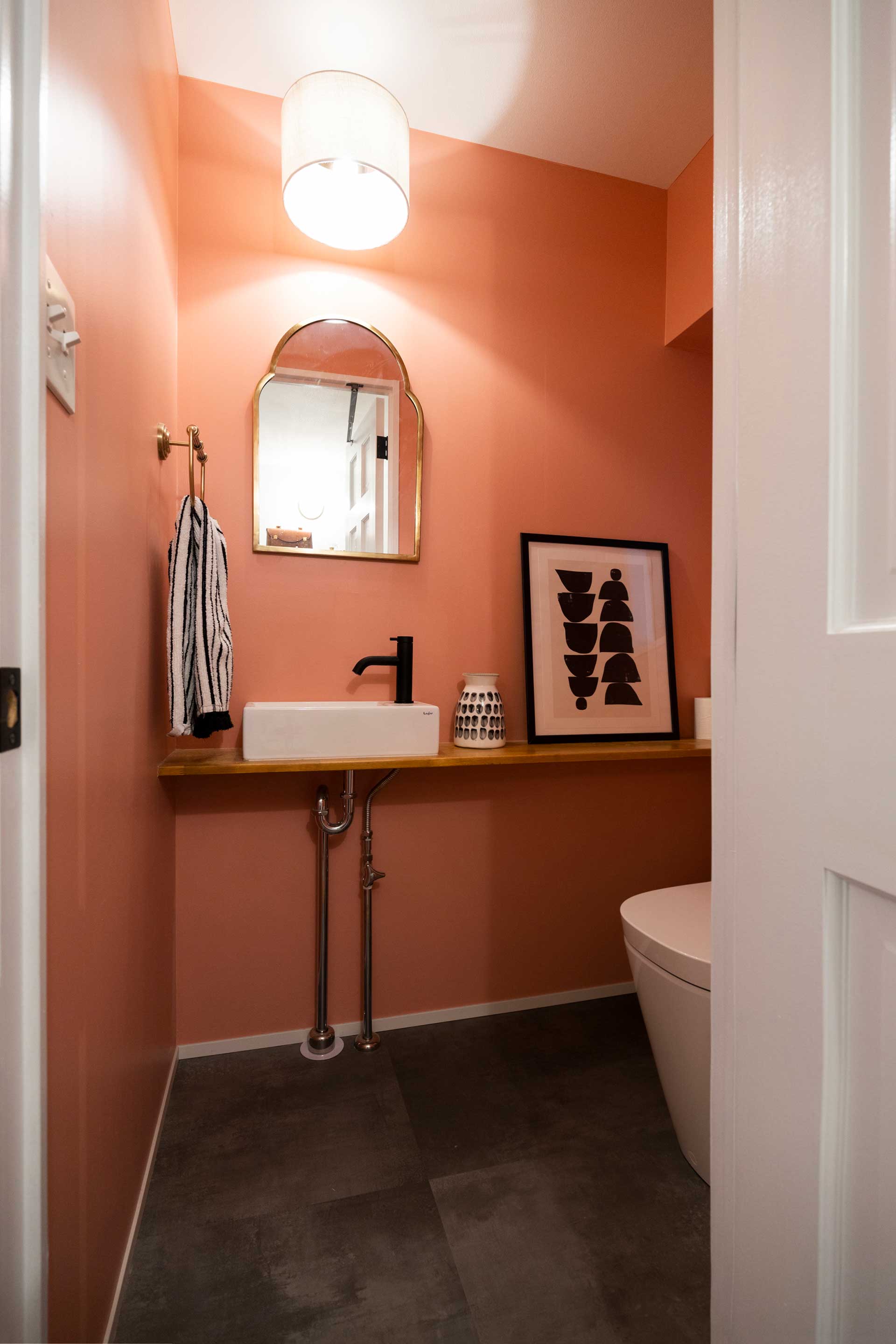トイレの壁はサーモンピンクに塗った。黒とゴールドの小物で空間を締める。