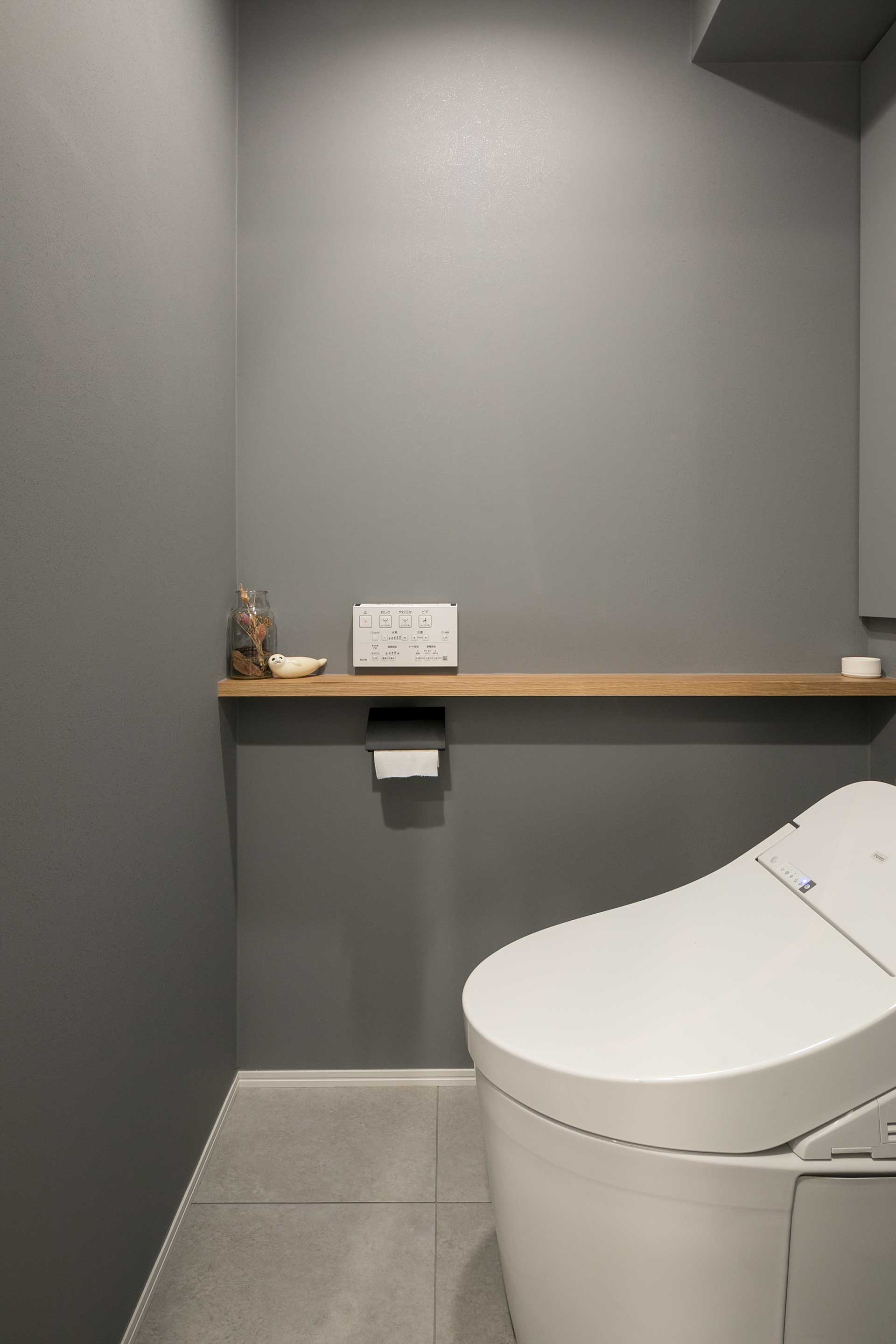 シンプルなトイレ。水回りはグレーのタイル敷きで統一している。