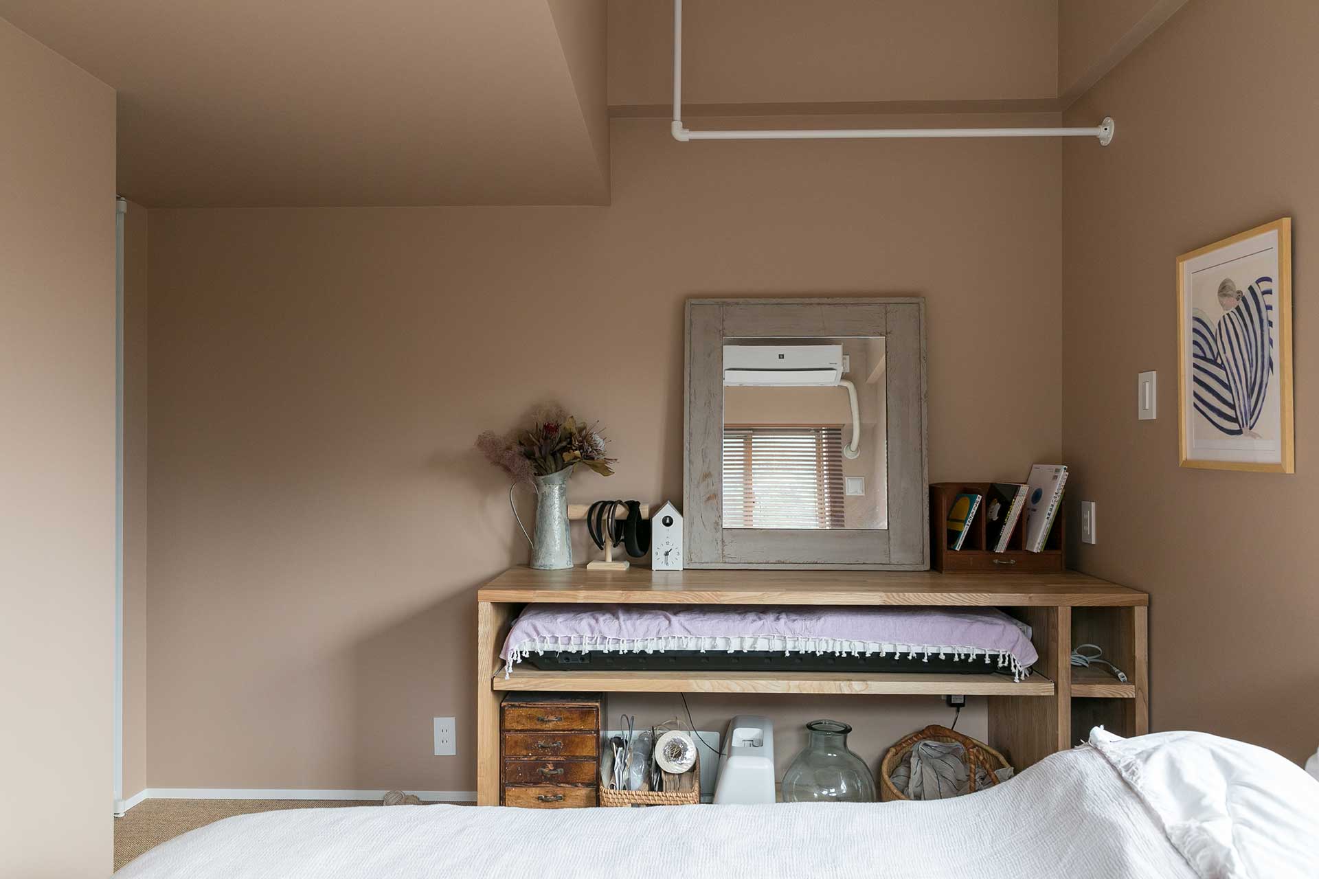 寝室にある造作カウンターは、天井につけられたポールを活用してアイロンがけをしたり、下部にあるスライドを引いて電子ピアノを出して弾いたりできる優れもの。