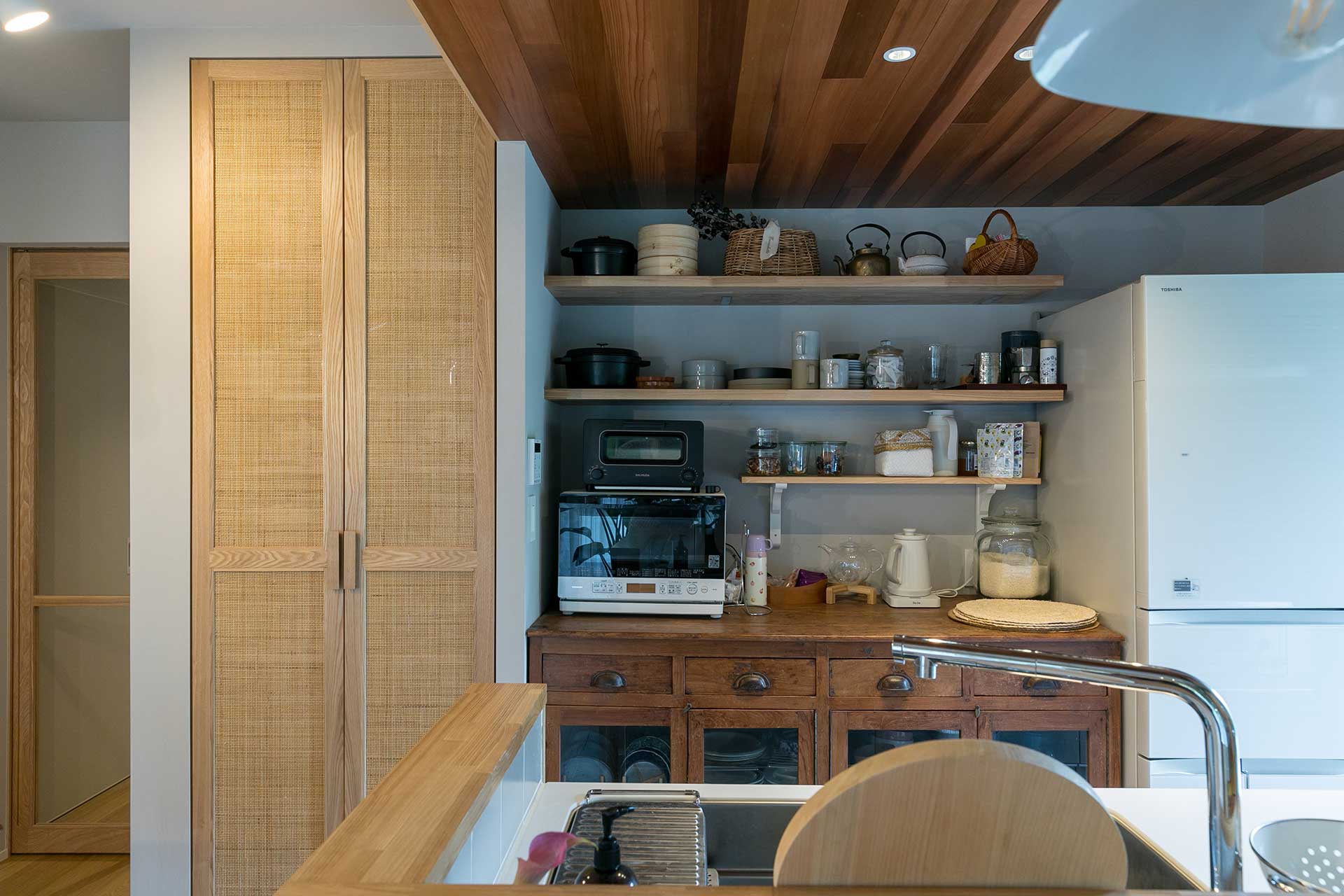 キッチンの背面はアンティークキャビネットのサイズに合わせ設計。グレーを基調とした空間の中にレッドシダーの天井材があることで、一層キャビネットが馴染む。