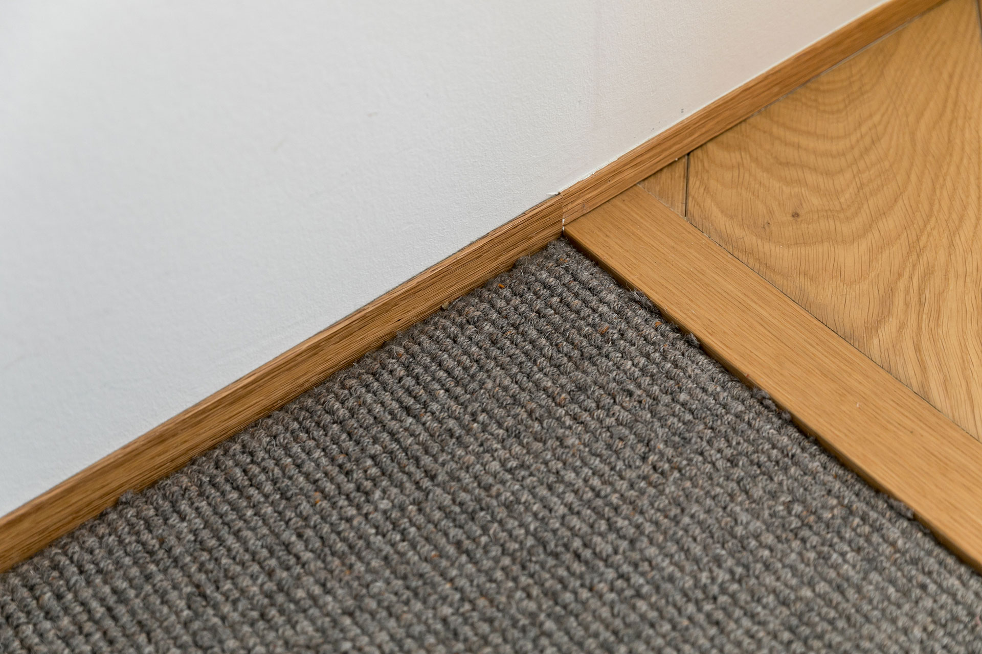 巾木は薄いウッドのものを選択。床材は柔らかなカーペットとフローリングを組み合わせている。