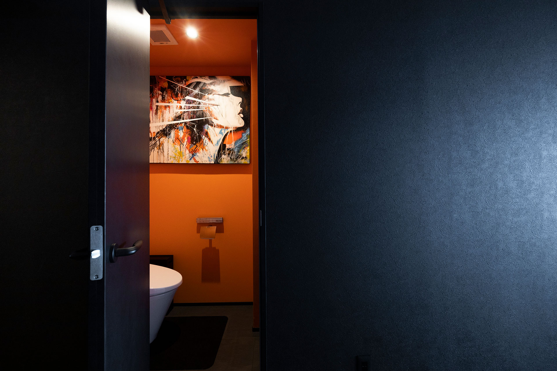 閉じられたトイレ空間は、大胆にオレンジ色の空間に。初めて購入したアートがぴったり似合った。