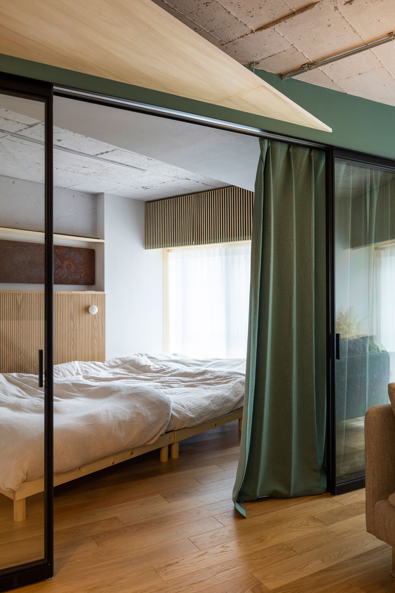 ベッドルームはガラスの引き戸とグリーンのカーテンで空間を分けることができる。