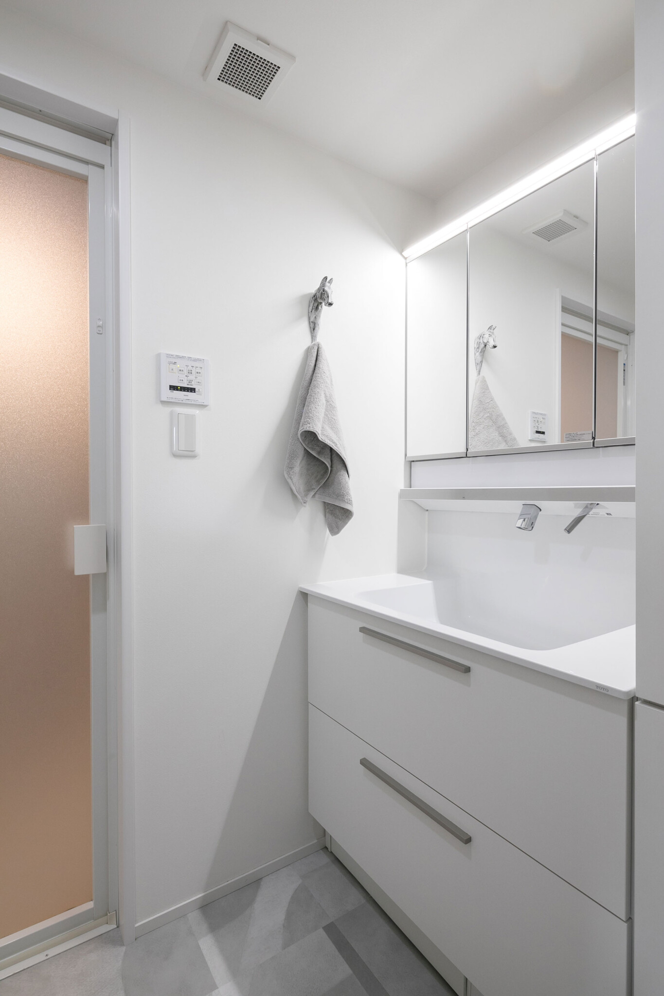 白で統一した洗面室。オブジェのような馬モチーフのタオル掛けがユニーク。