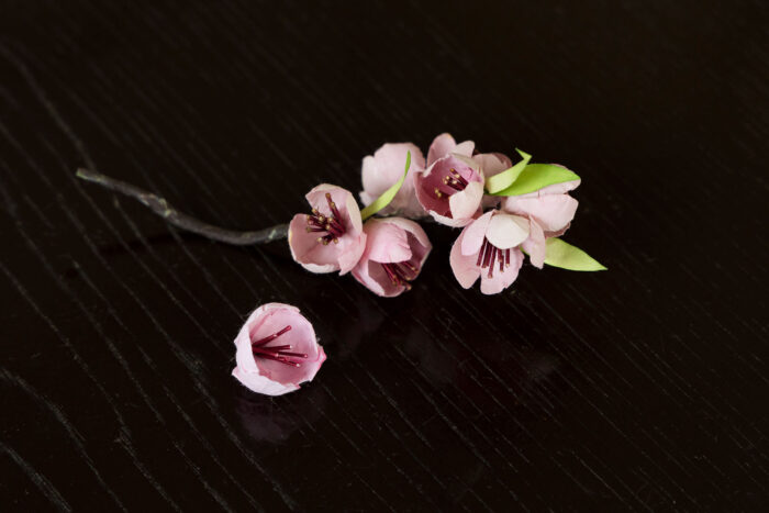 出来上がった桃の花を、緑の若葉を添えてワイヤーでつなげて茶色の紙テープで巻くと、桃の花の枝先になる。