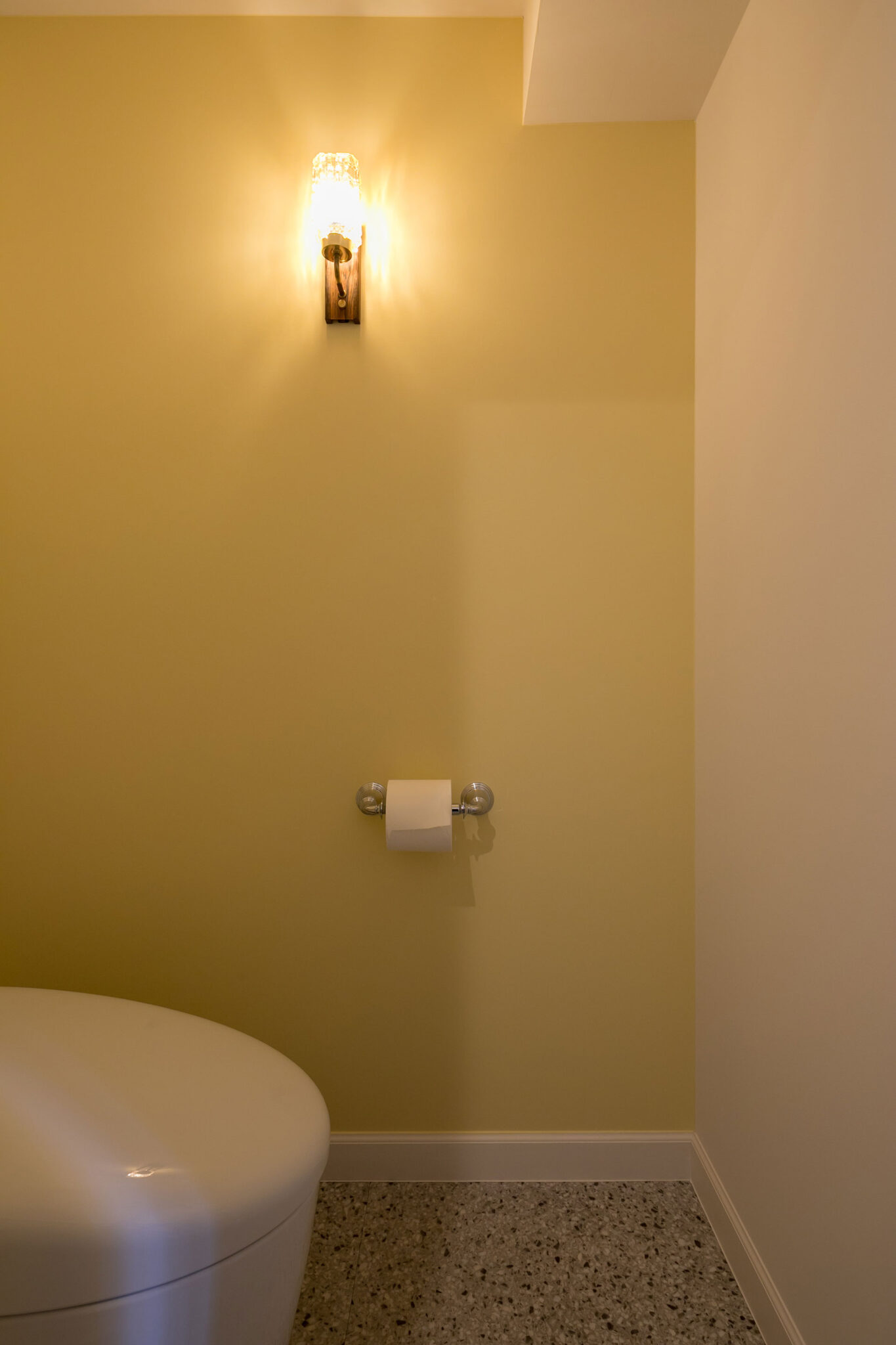 アクセントカラーに壁一面をクリームイエローにし、「コーラー」のトイレットペーパーホルダーを取り付けた。