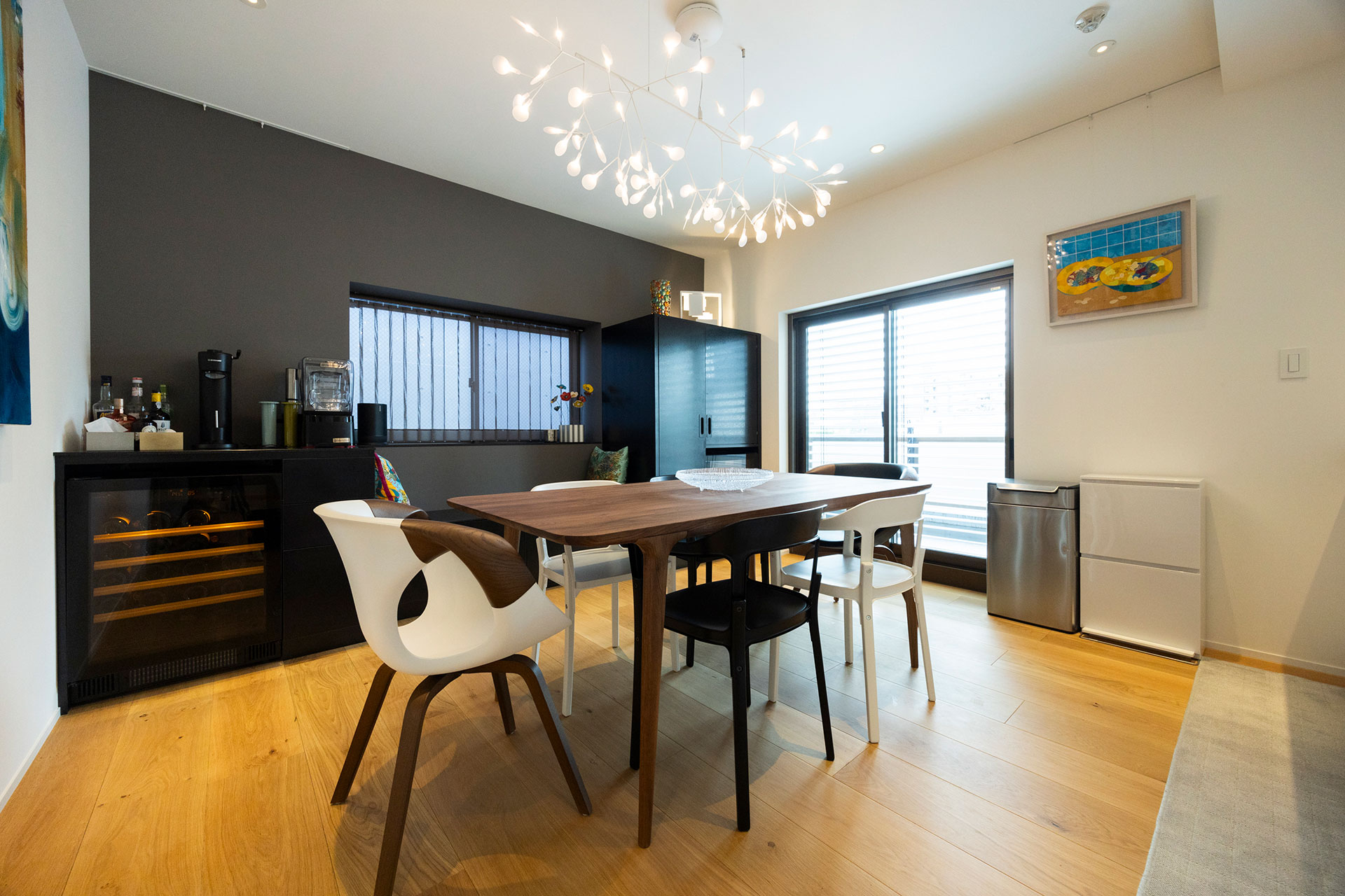 ダイニング側の一面にグレーの壁紙を採用。空間のカラーコンセプトに合わせる形で、イタリアブランドのイスをセレクトした。グレーの壁前の両サイドの棚の間には、下が収納になったベンチが設けられている。照明はmoooi。