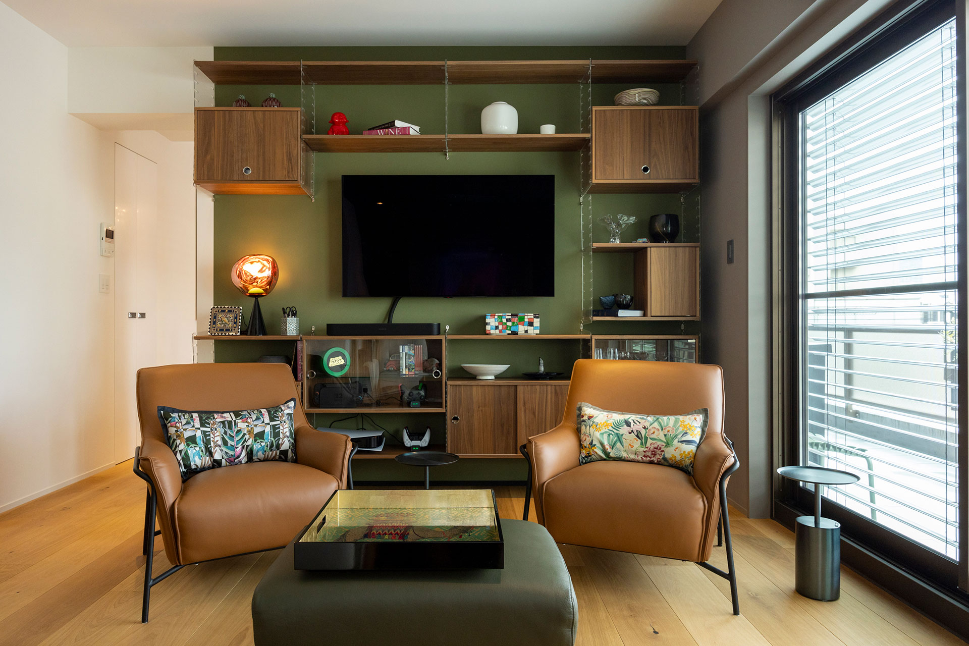 ブラウン×グリーンのカラーでコーディネートしたラウンジ。スウェーデンの壁掛け収納家具Stringを設置。イタリアの小さな村で作家につくってもらった器など、海外で入手した雑貨を飾っている。Tom Dixonのサイドライトは夜、自動点灯する仕組みに。