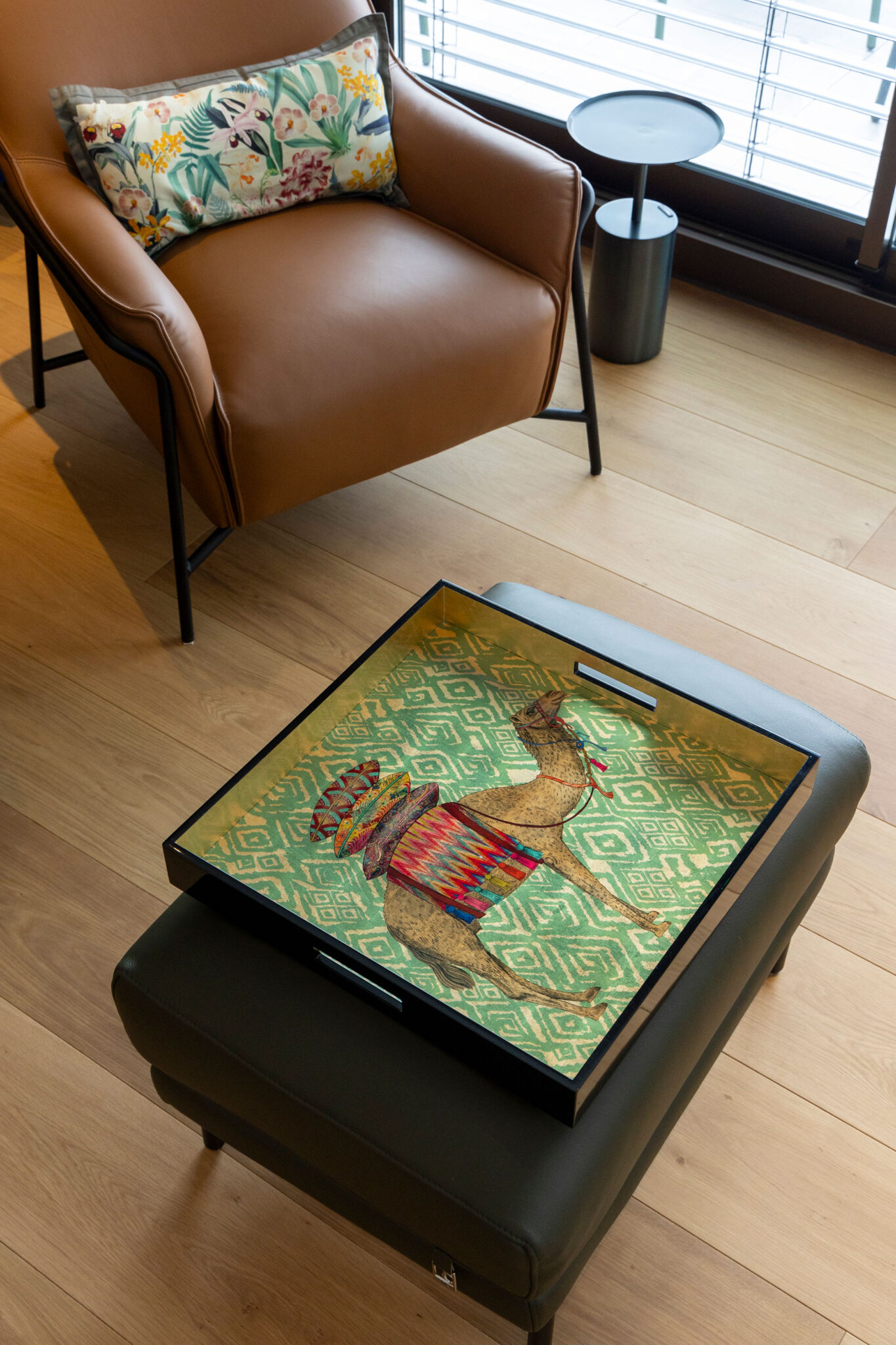 ソファテーブルは置かず、あえてオットマンの上にトレーを置くスタイルに。チェアには1脚ずつ小さなサイドテーブルを添えている。