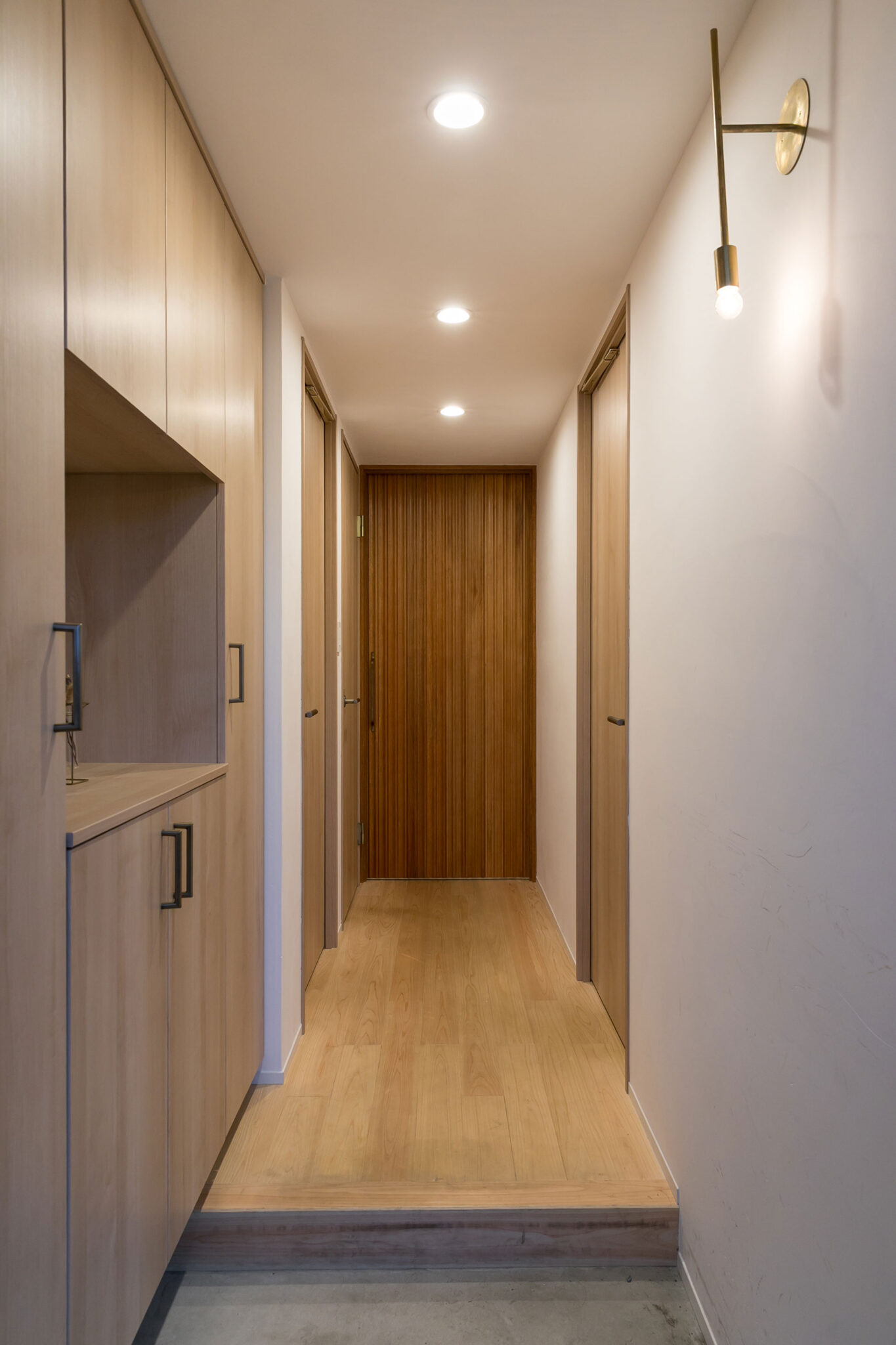 玄関の床材はモルタル、真鍮製のブラケットライトは「千sen」を採用。