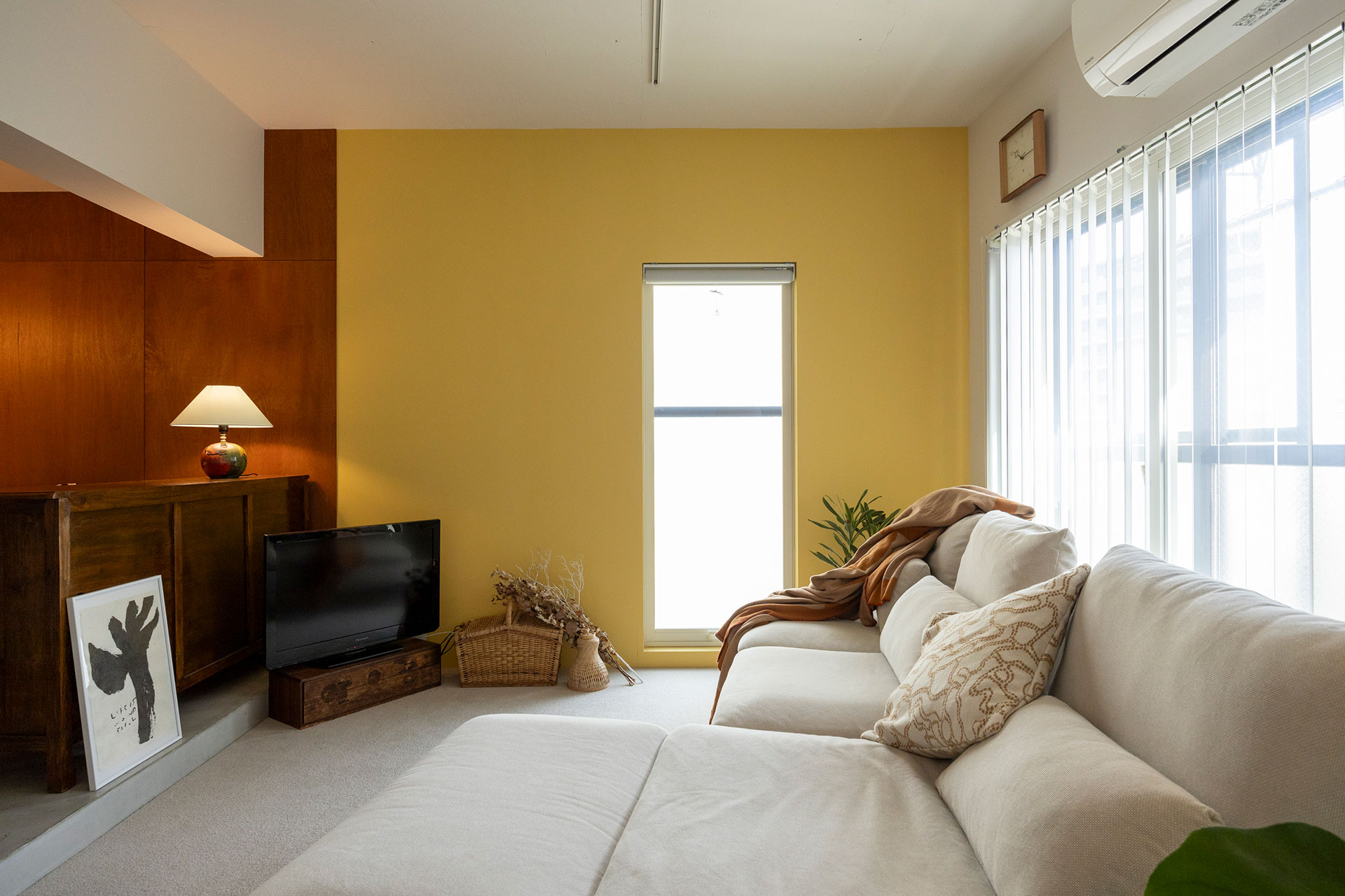 壁の一面をポルトガルのポルトで見たカラーに塗装。ダイニングから雰囲気が切り替わるものの、同じイエローベースで繫がっているためか違和感がない。テレビ台はダイニングからテレビが見えない高さになるものをチョイス。