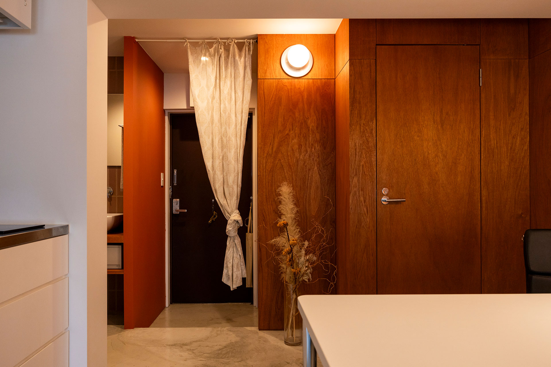 玄関はインドで購入したブロックプリントの布で仕切っている。ラワンの壁を「toolbox」の壁付け照明が照らす。