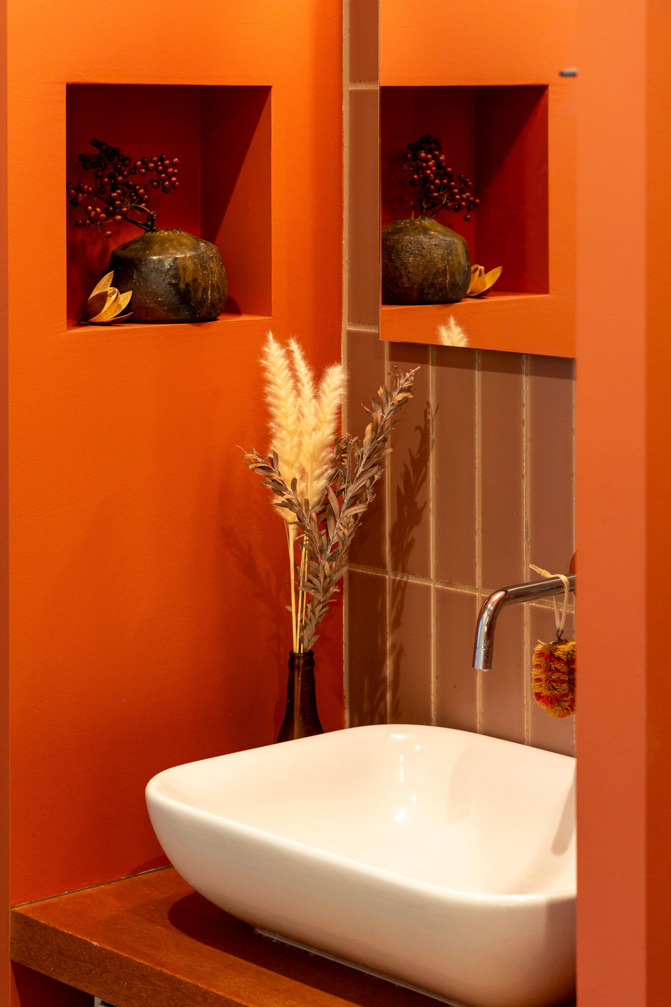 洗面台の棚板にもラワン材を採用。タイルは縦貼りで。明るめのレッドが非日常感を出している。