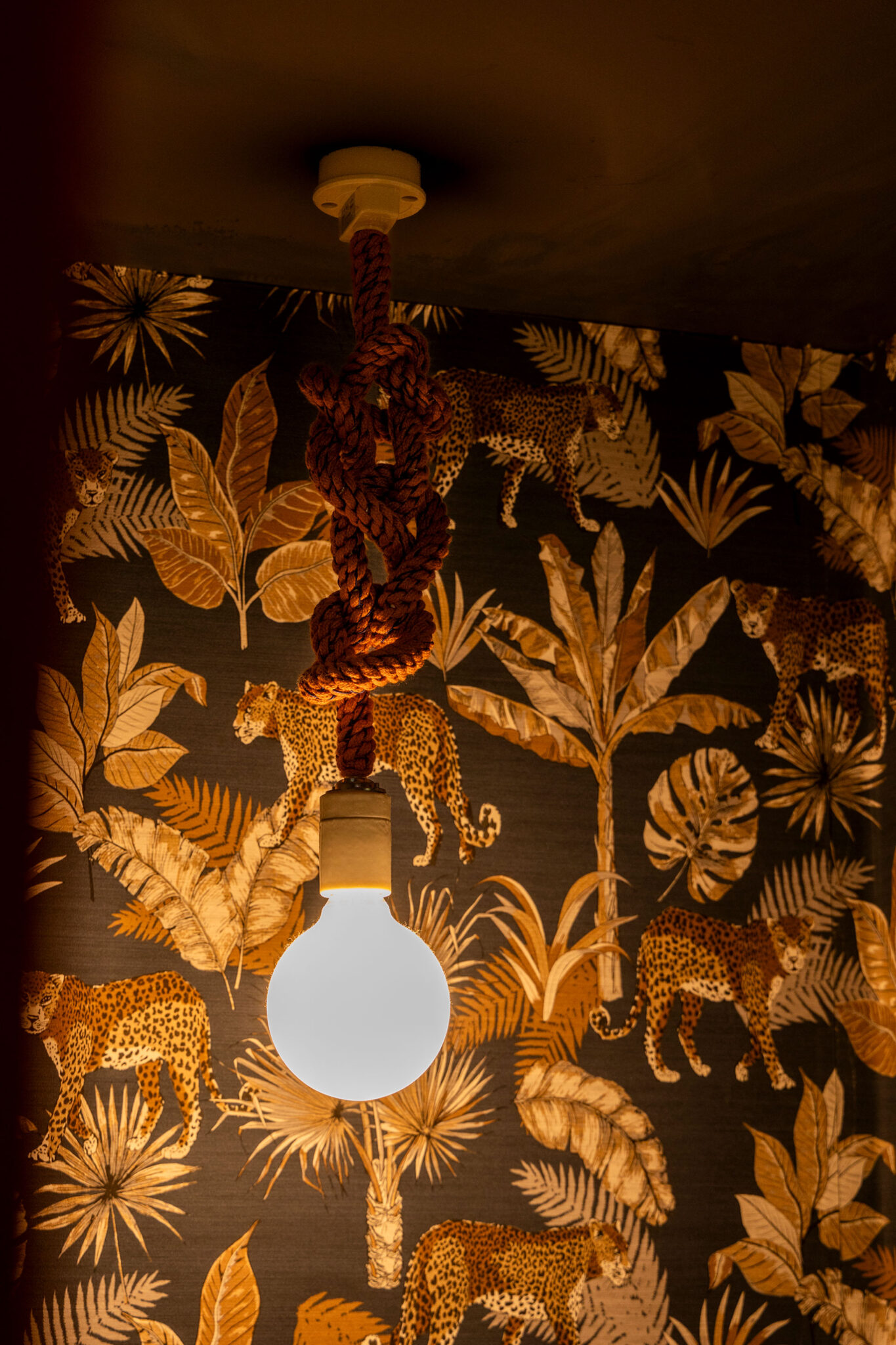 「壁紙本舗」の壁紙を使ったトイレ内。ジャングル柄と「toolbook」の手編みロープ照明がマッチしていて楽しい。