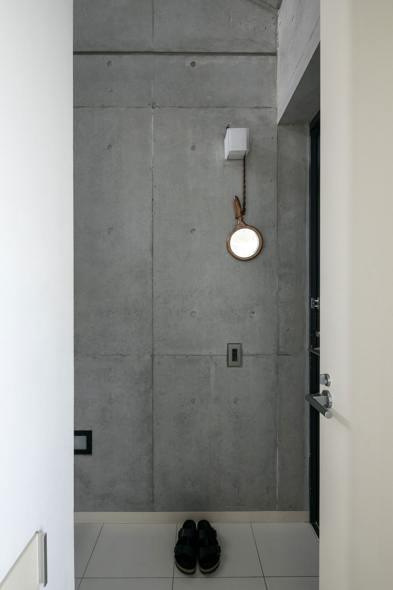 コンクリート打ち放しの壁とタイルの玄関。