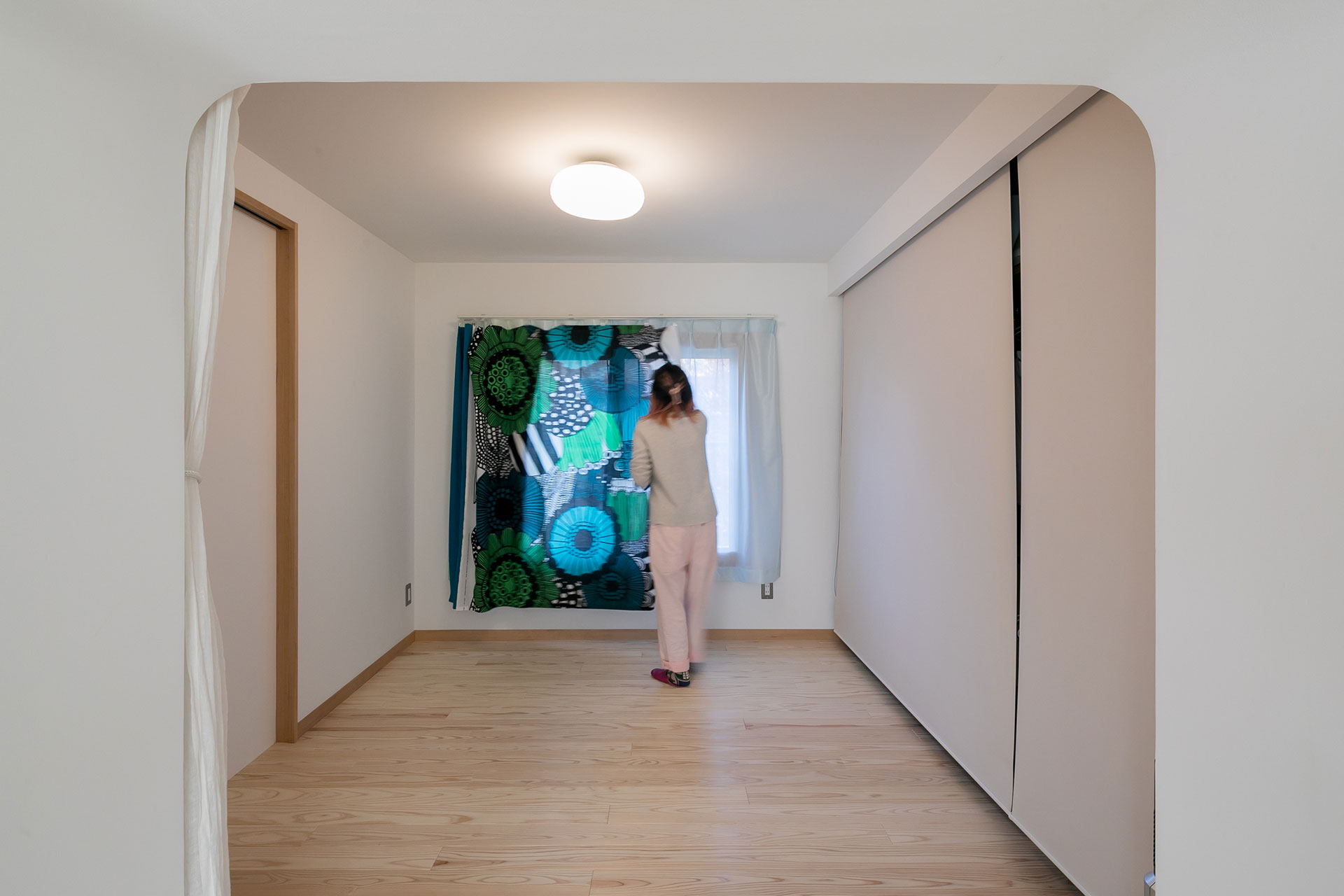 寝室のカーテンは、Oさんがマリメッコの布を手縫いしたもの。鮮やかな色柄が寝室をポップに彩る。