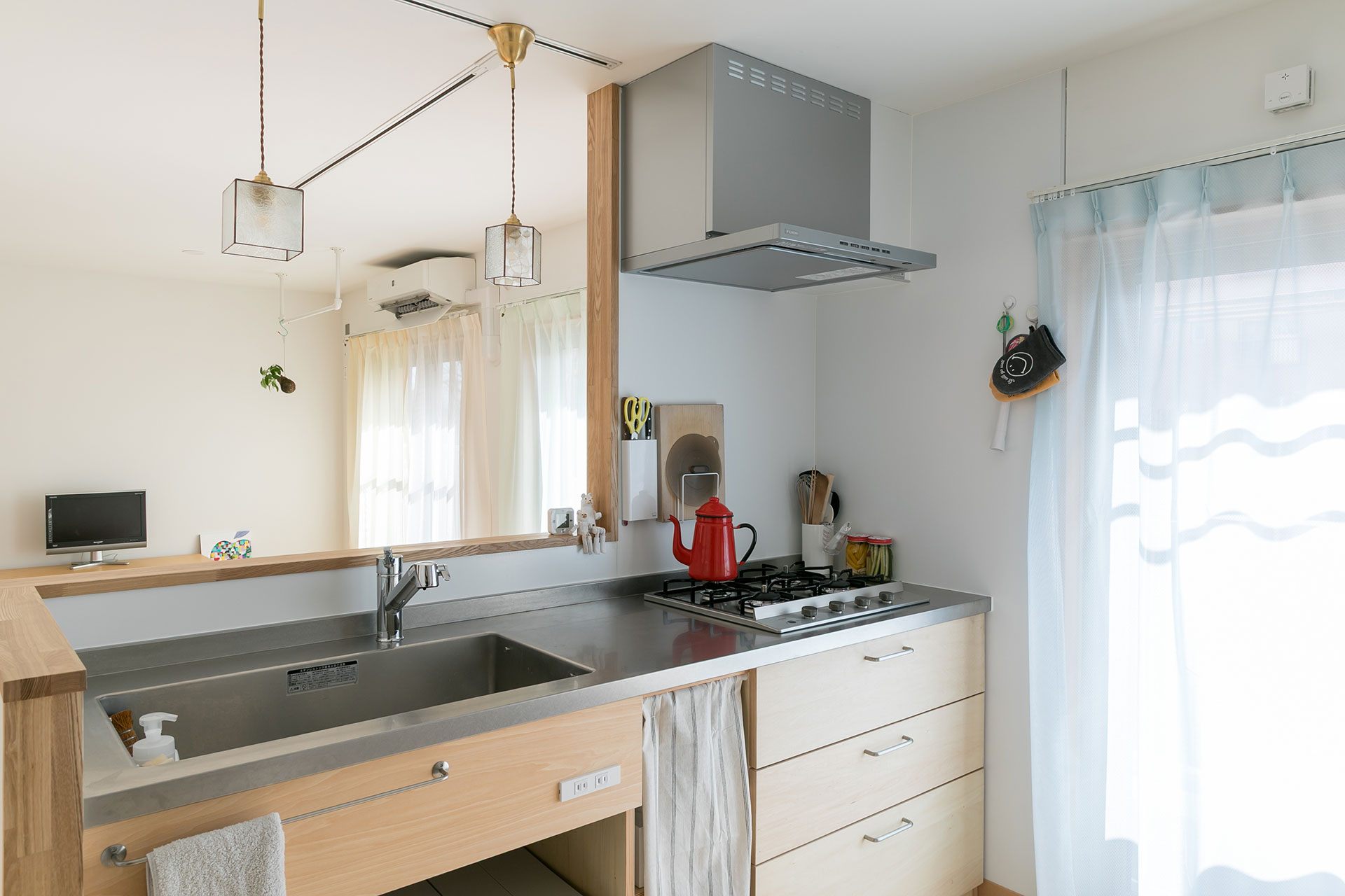 既存のキッチンの向きを180度移動して、対面式に。キッチンはシナ材で造作した。ペンダントライトはレトロなガラスを使ったものをOさんが選んだ。