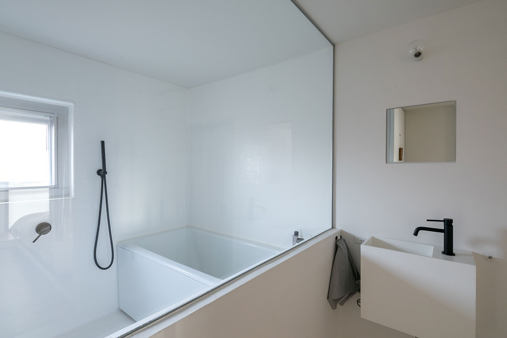 FRPの白の空間に、 ホーローの白の浴槽。シャワーヘッドの黒がアクセントに。洗面の水栓も黒。