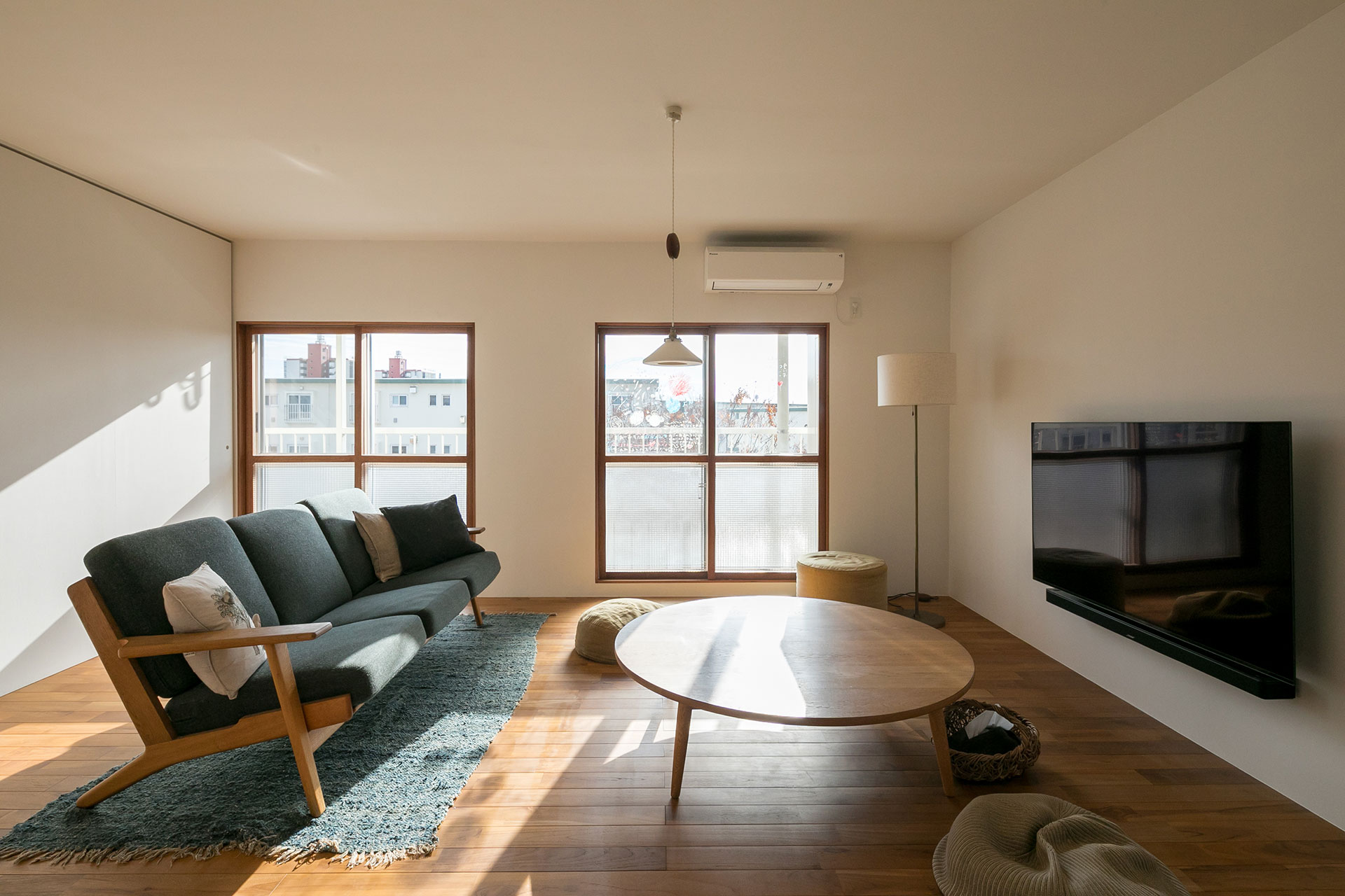 優しい日差しが入る窓に、木製の内窓をつけた。ソファーはハンス・J・ウェグナー。「壁付のTVはDYでつけました」