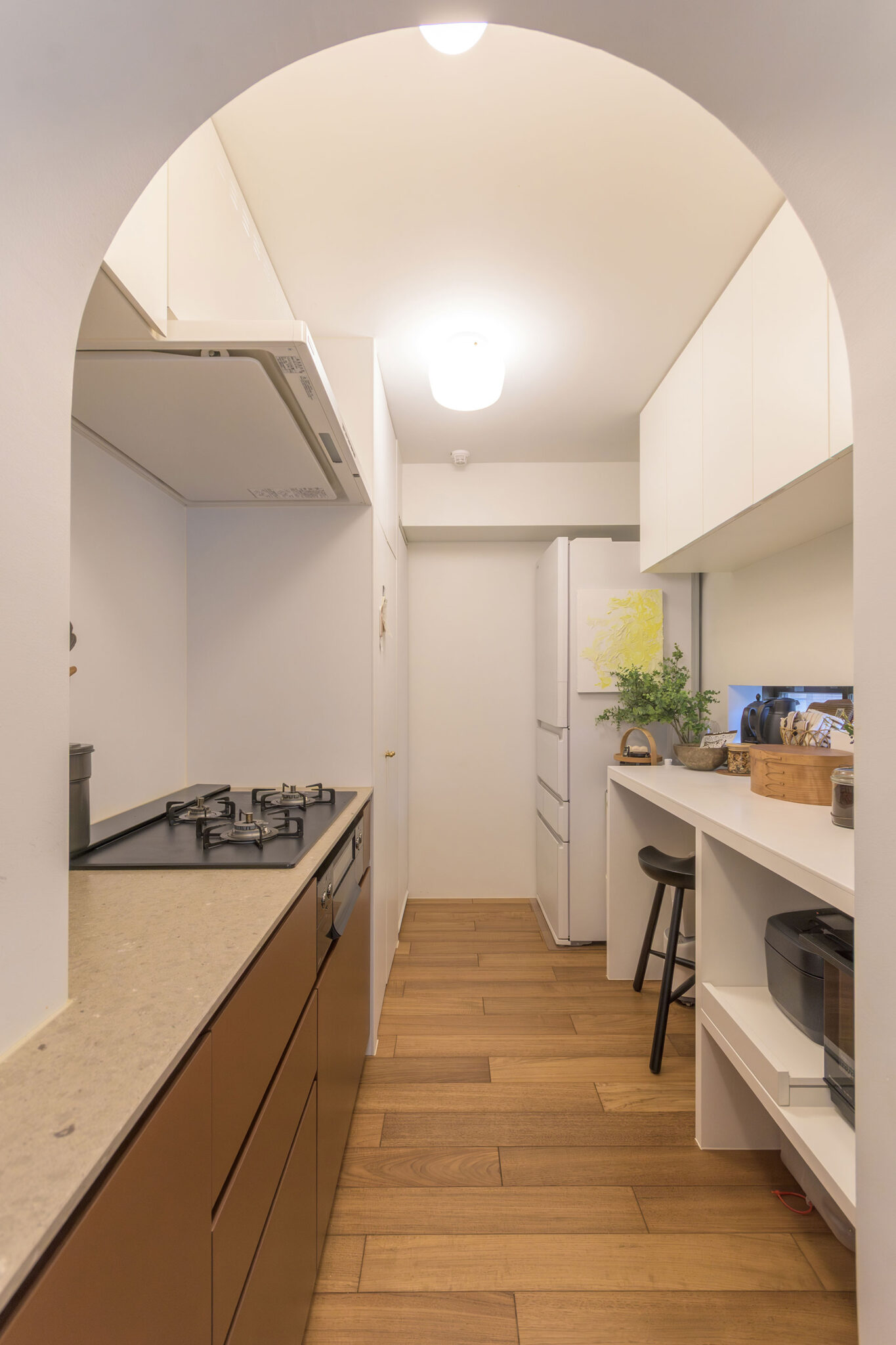 キッチンをゆるやかに仕切るRの開口の先は、クローズキッチンに。生活感のでやすいコンロや家電などを配置。