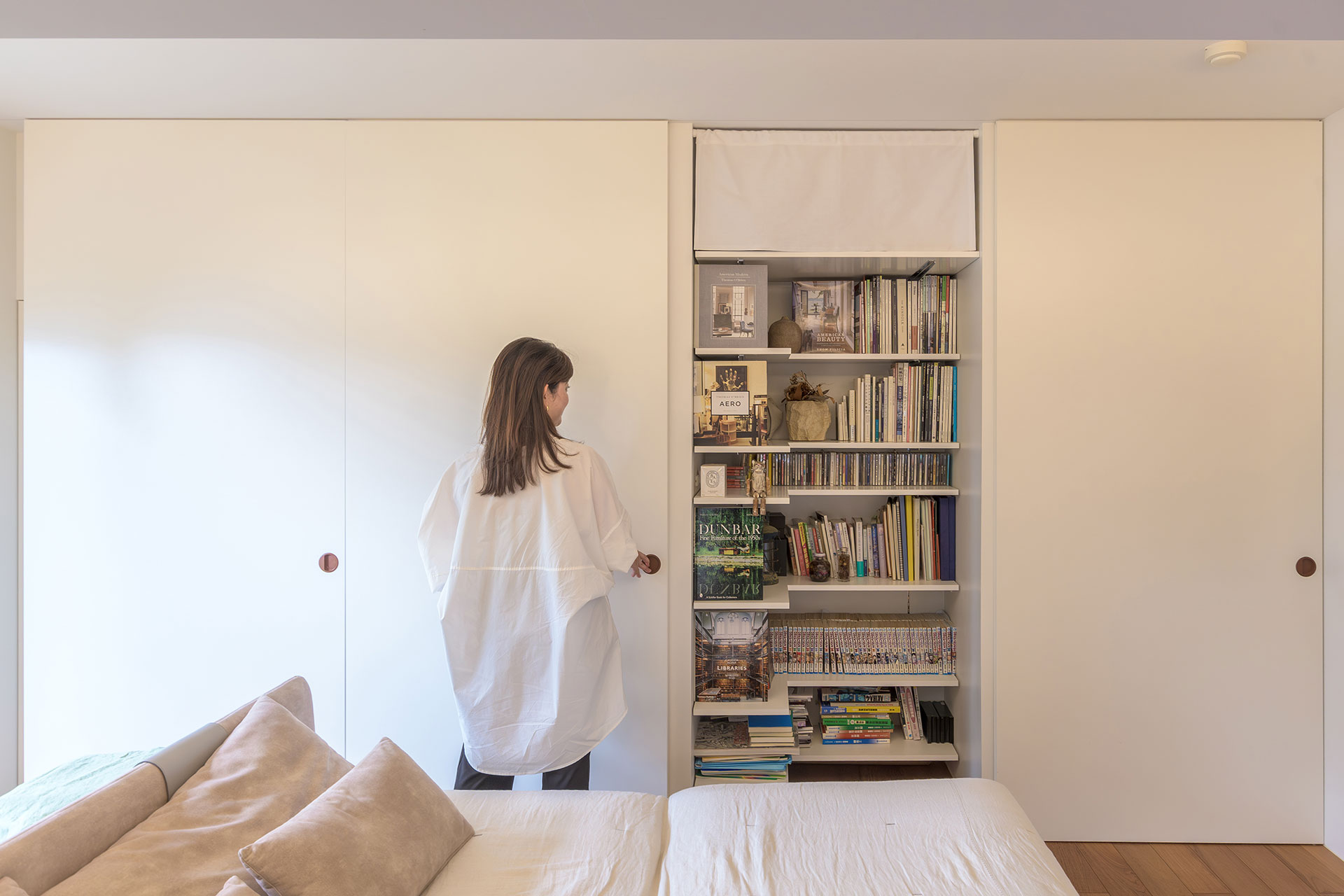 リビングの壁一面に設けた収納の内部にはL字の棚板を設け、書籍、キャンプ道具、季節のアイテムなどが一目で見やすく収納されている。